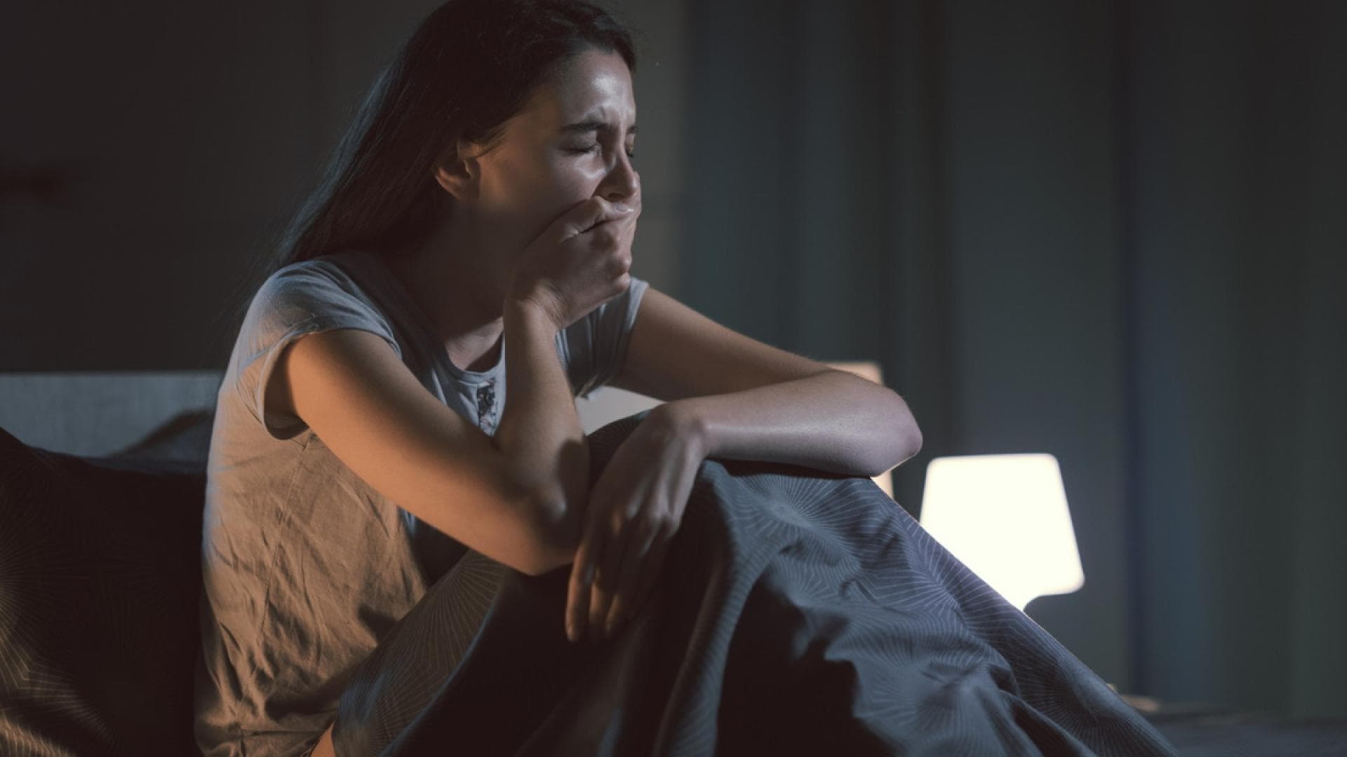 Müde Frau gähnt mitten in der Nacht im Bett
