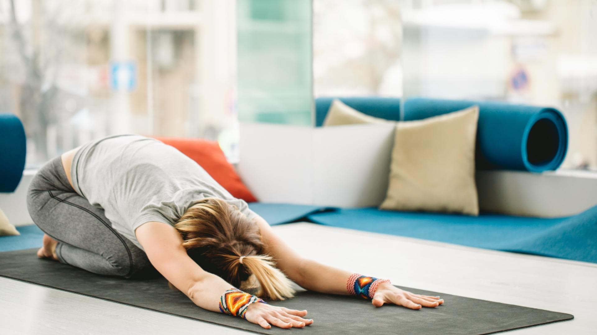 Frau macht Dehnübung auf Yoga-Matte