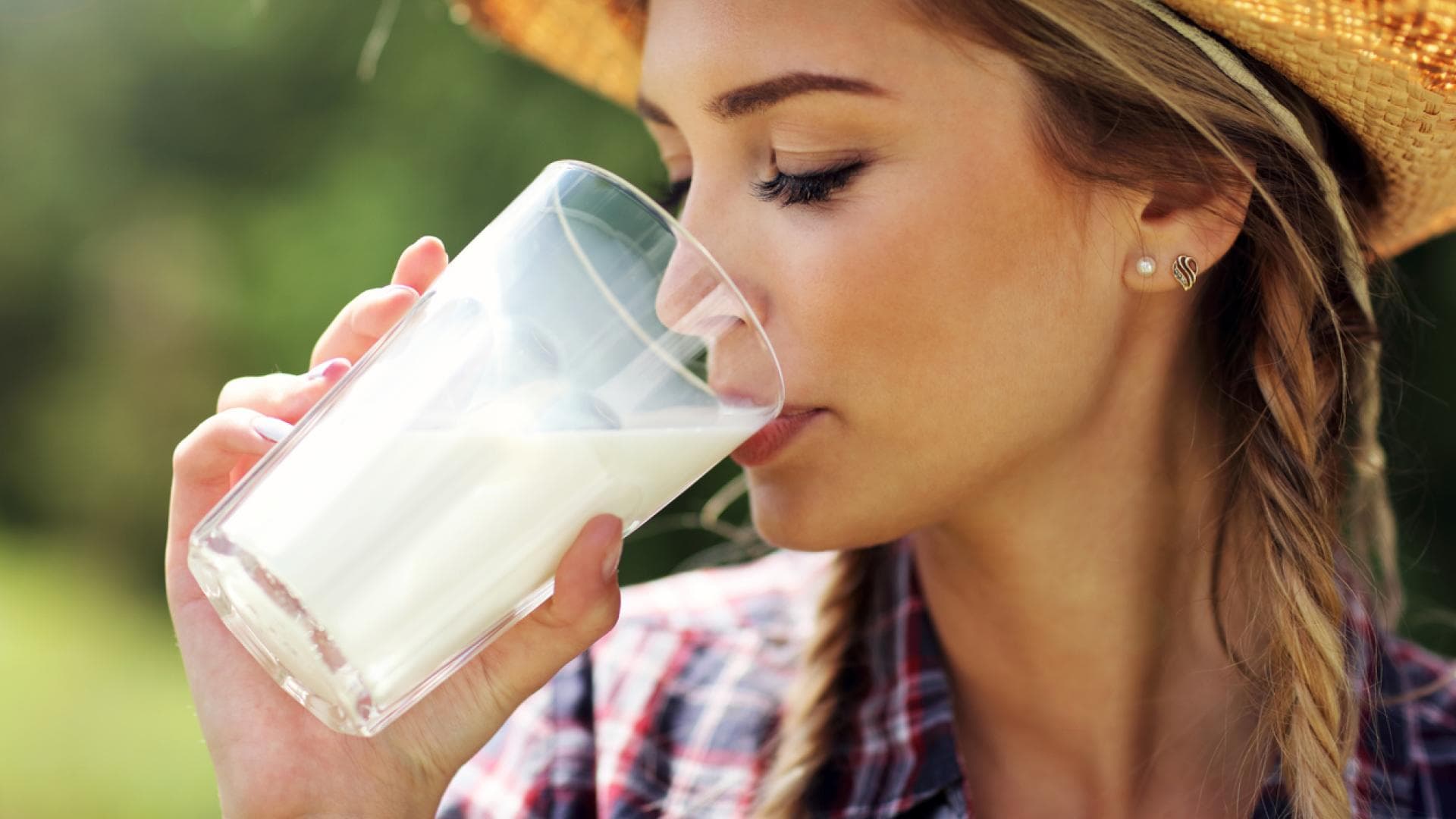 Frau mit Hut trinkt Milch aus Glas