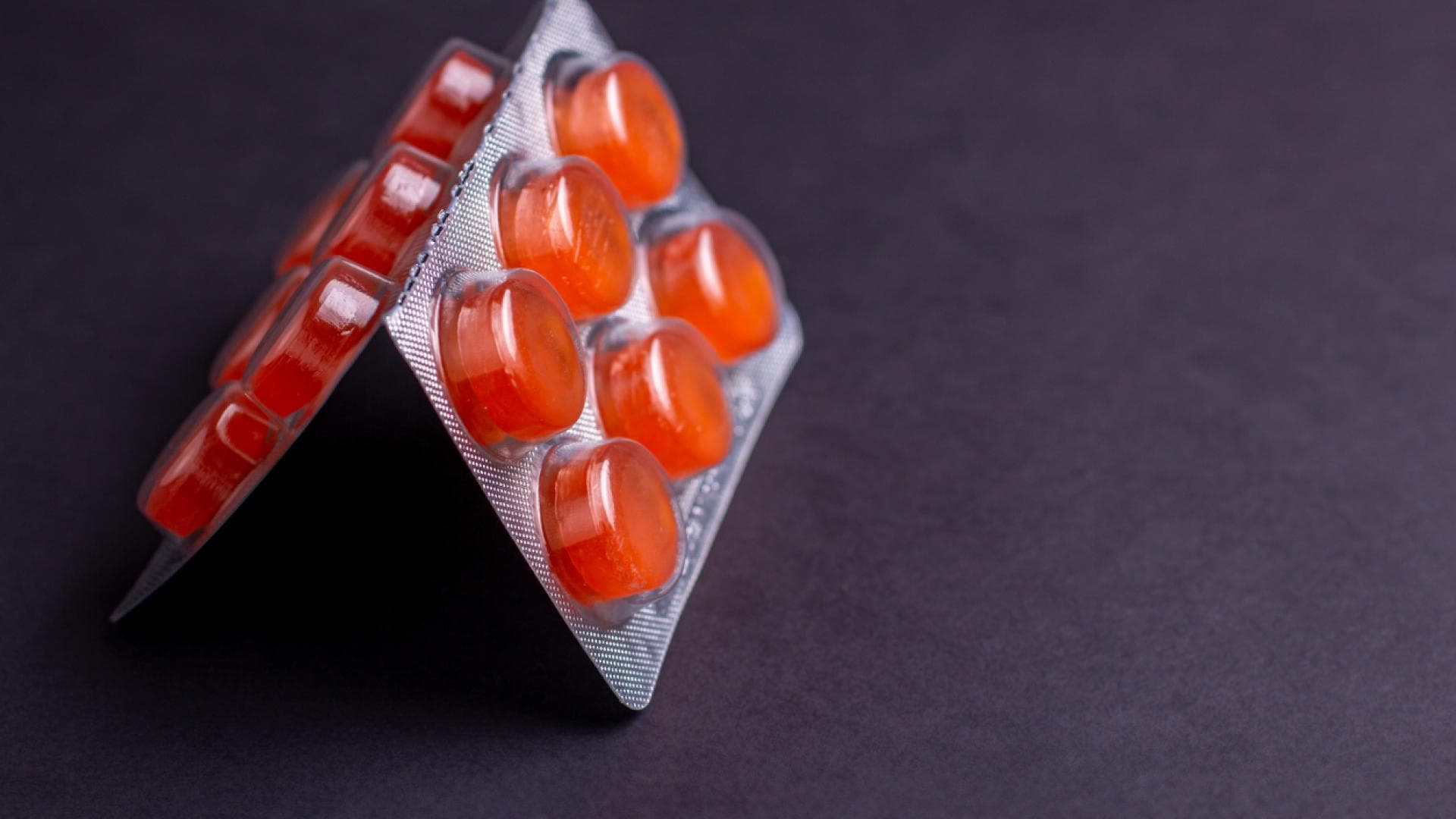 Halsschmerztabletten auf schwarzem Untergrund