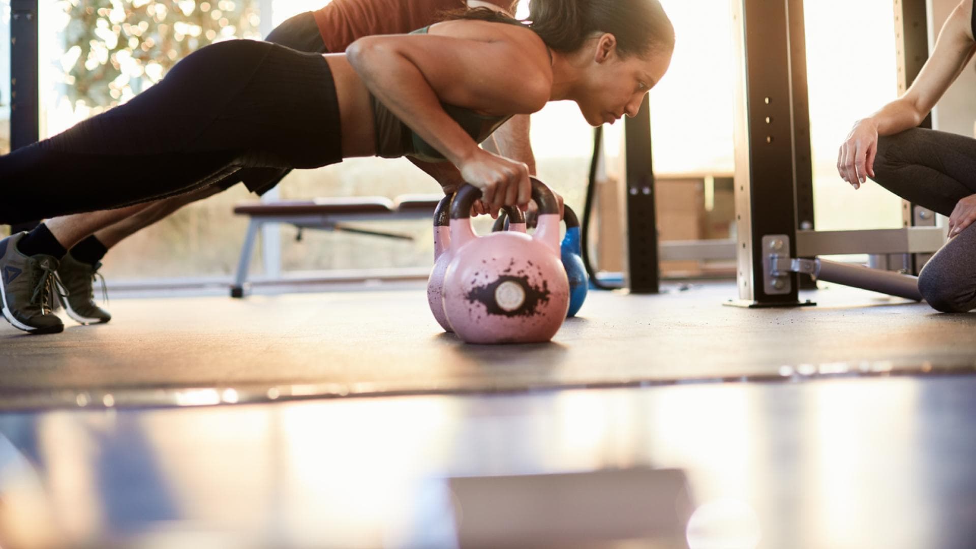 Liegestützt mit Griffen oder Kugelhantel Frau macht Liegestütz mit Kettlebells
