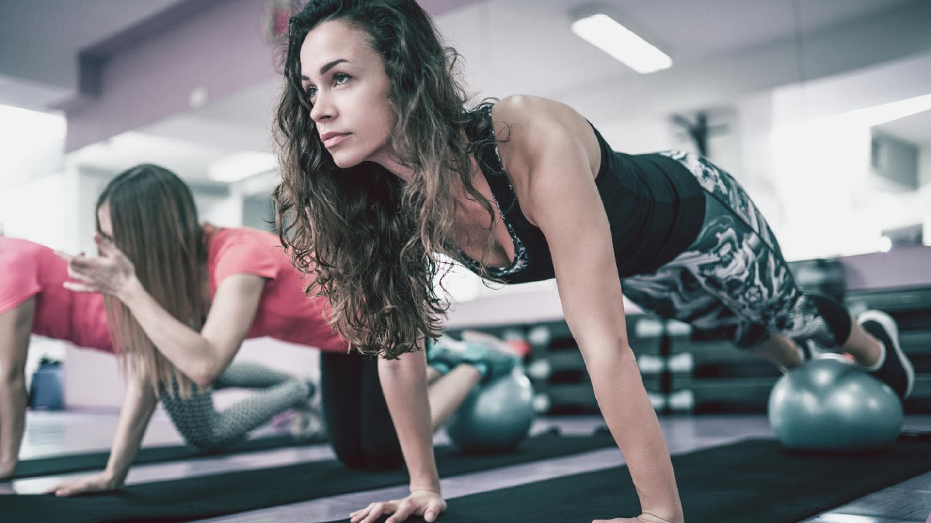 Push-ups mit erhöhten Beinen Frau macht Liegestütz auf Gymnastikball