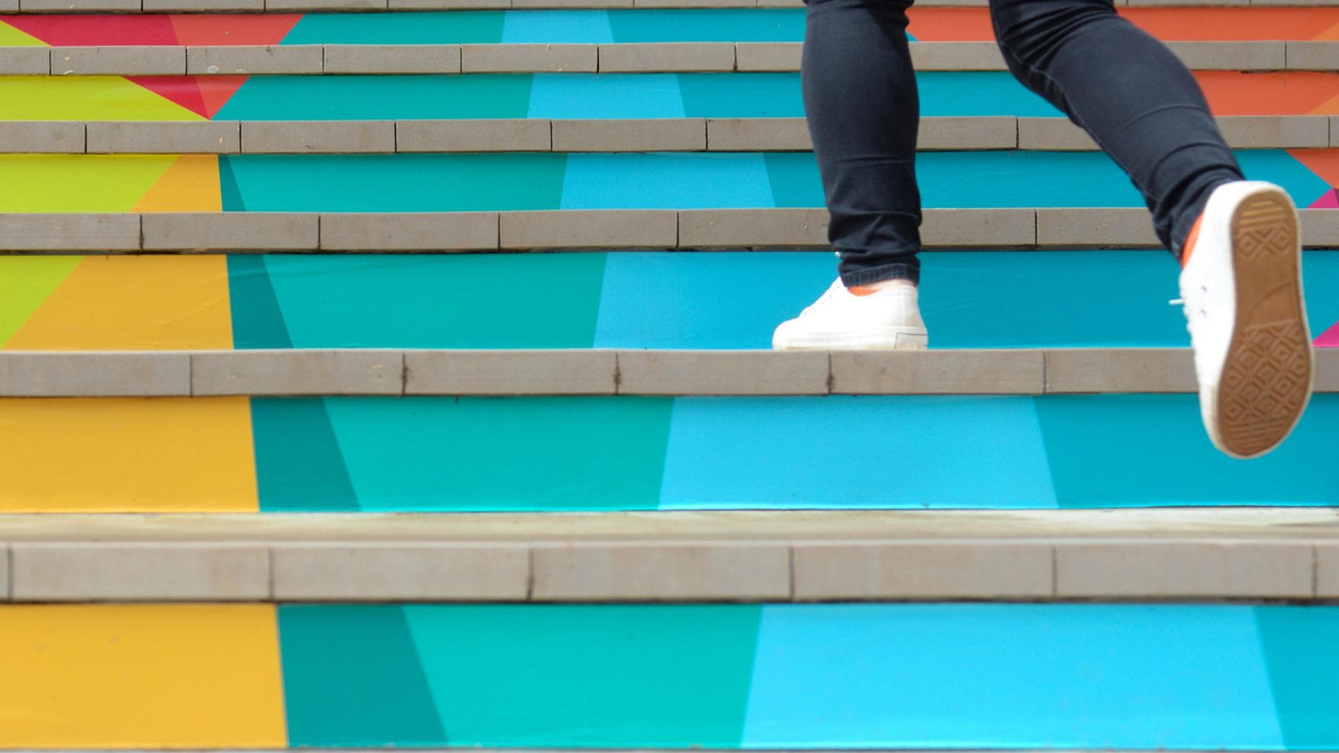 Mann geht bunte Treppen hoch