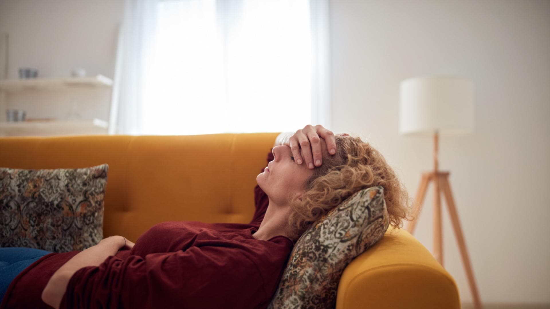 Frau mit Kopfschmerzen liegt auf Sofa