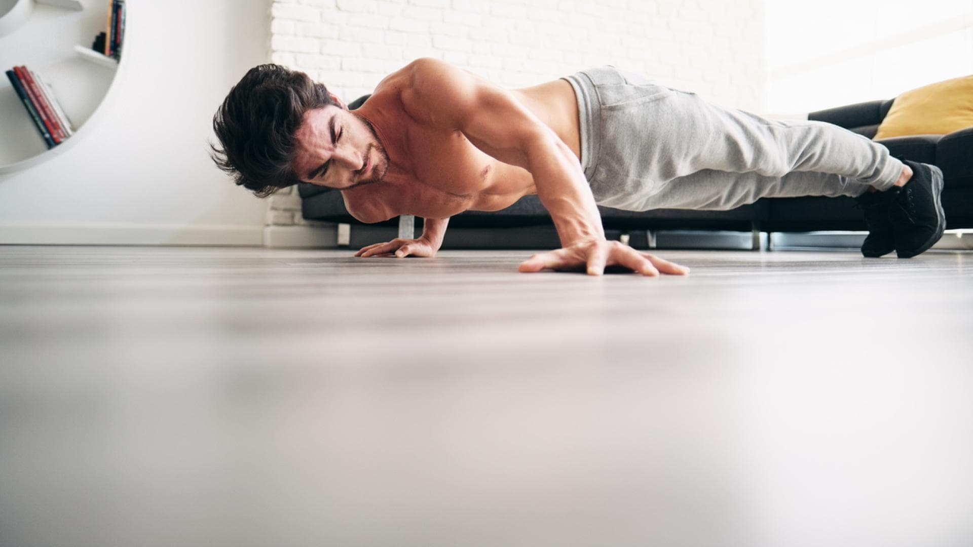 Die Variante erfordert viel Körperkontrolle Mann macht Archer Push-ups in der Wohnung