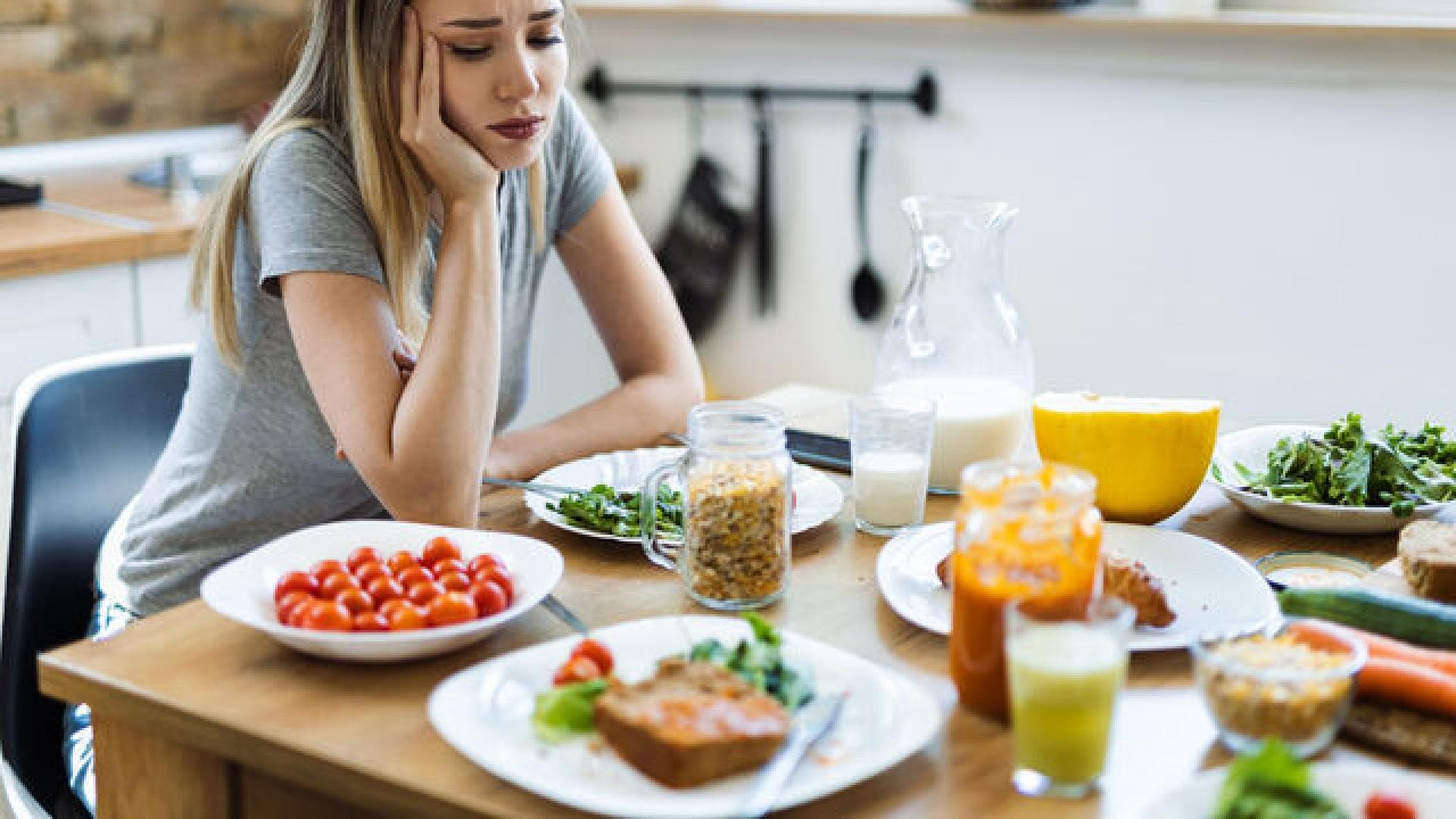 Manchmal kann auch Stress die Lust am Essen verderben. Frau sitzt lustlos vor einem vollem Teller