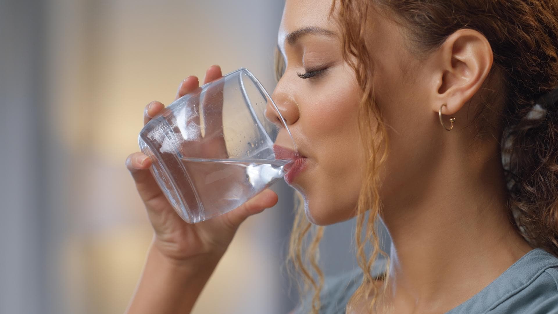Frau trinkt Wasserglas.
