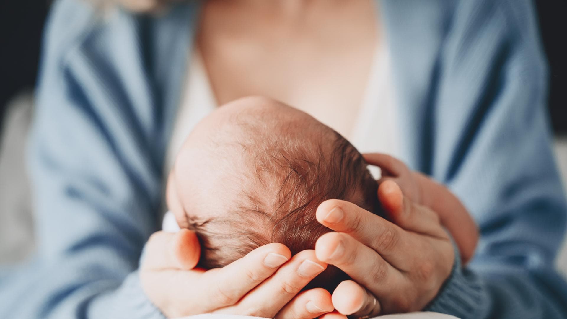 Mutter hält Neugeborenes in der Hand
