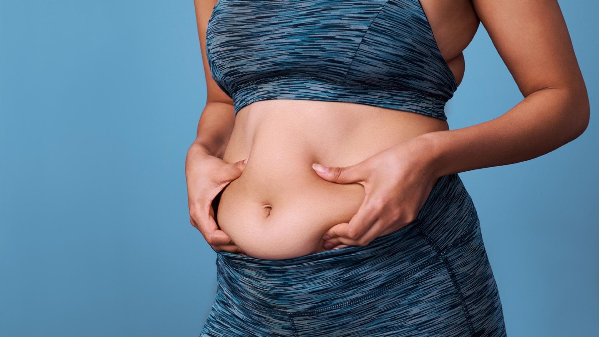 Frau in Sportsachen hält sich Bauch