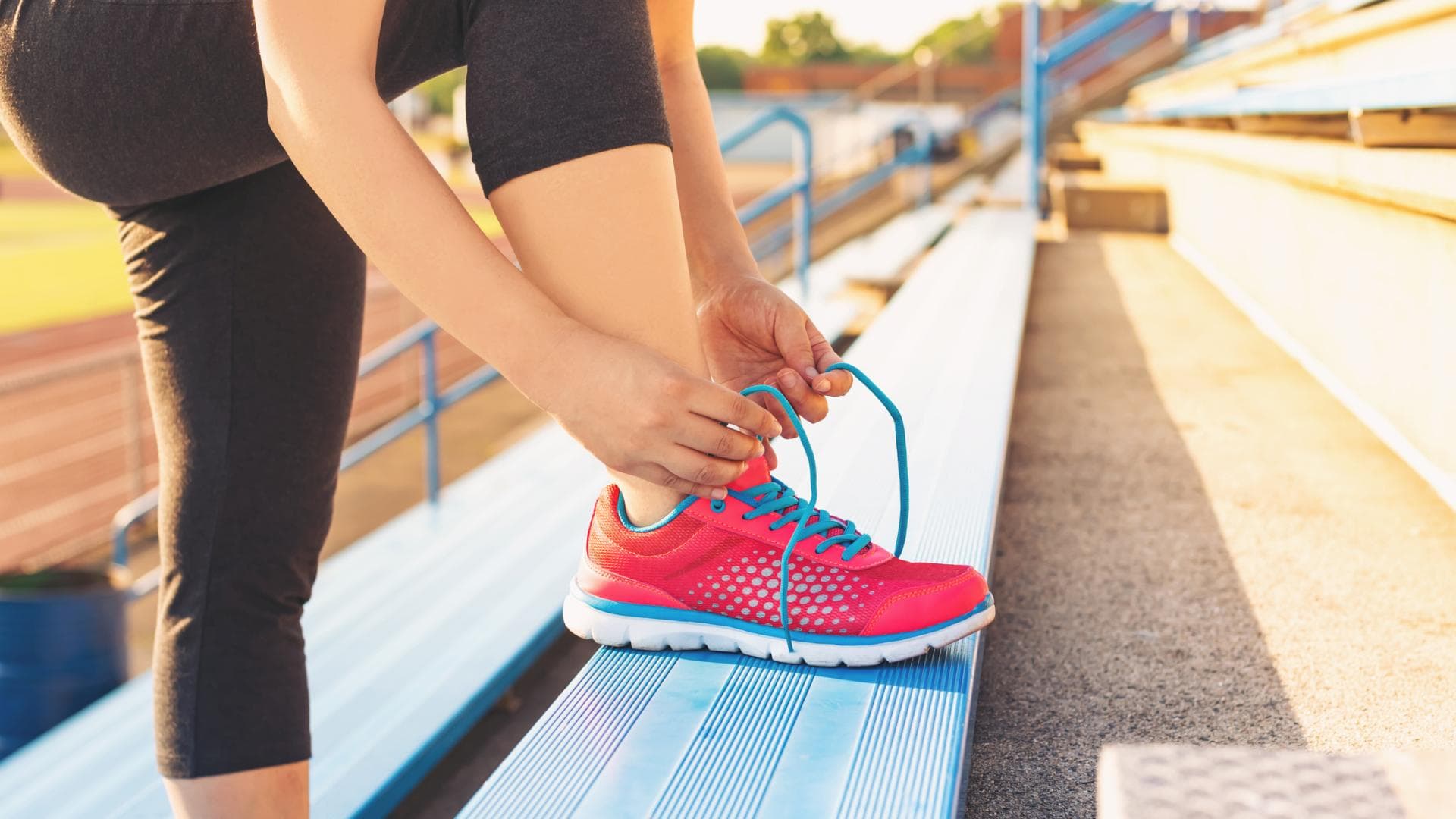 Frau auf Treppe bindet sich Sportschuhe zu