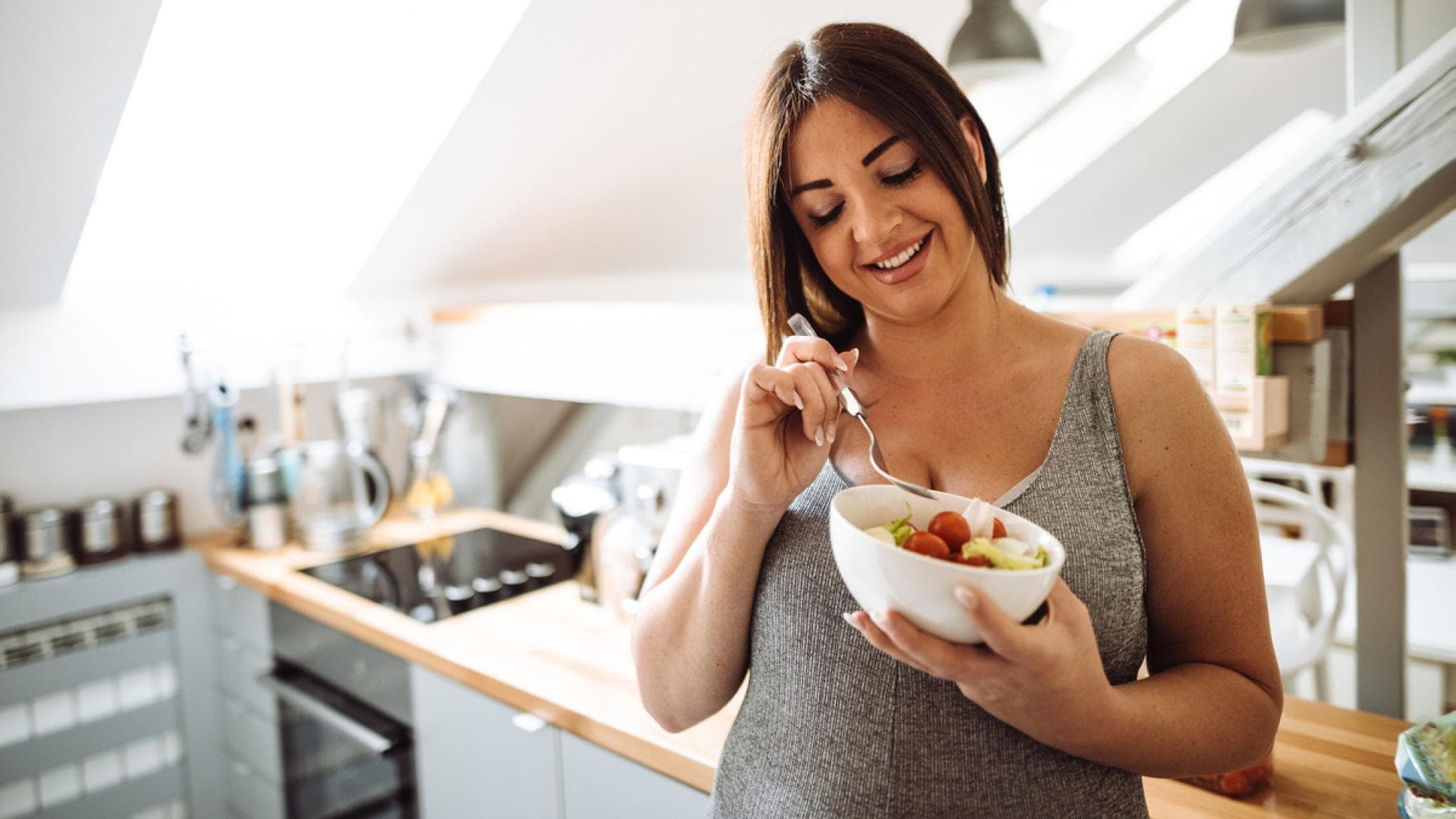 Schwangere Frau isst Obst in Küche