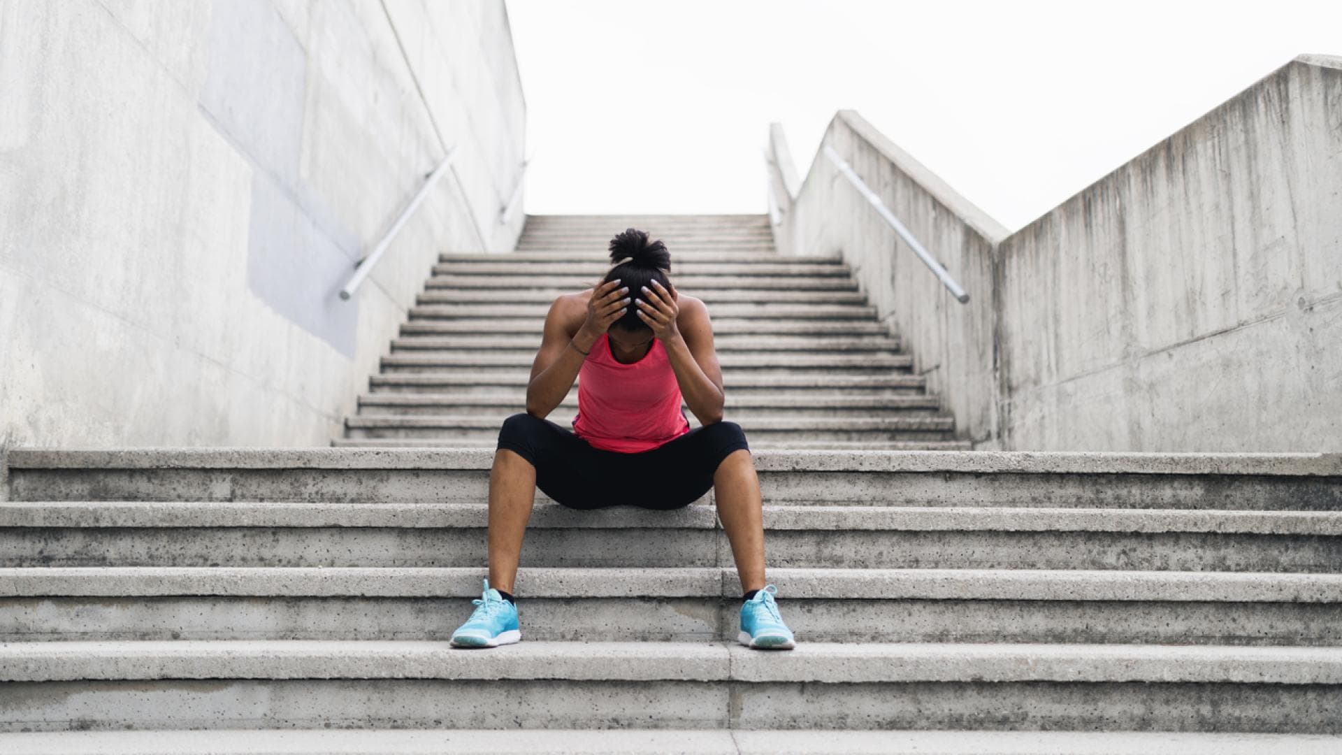 Schwindel beim Sport nicht selten Joggerin sitzt mit Schwindel auf Treppe