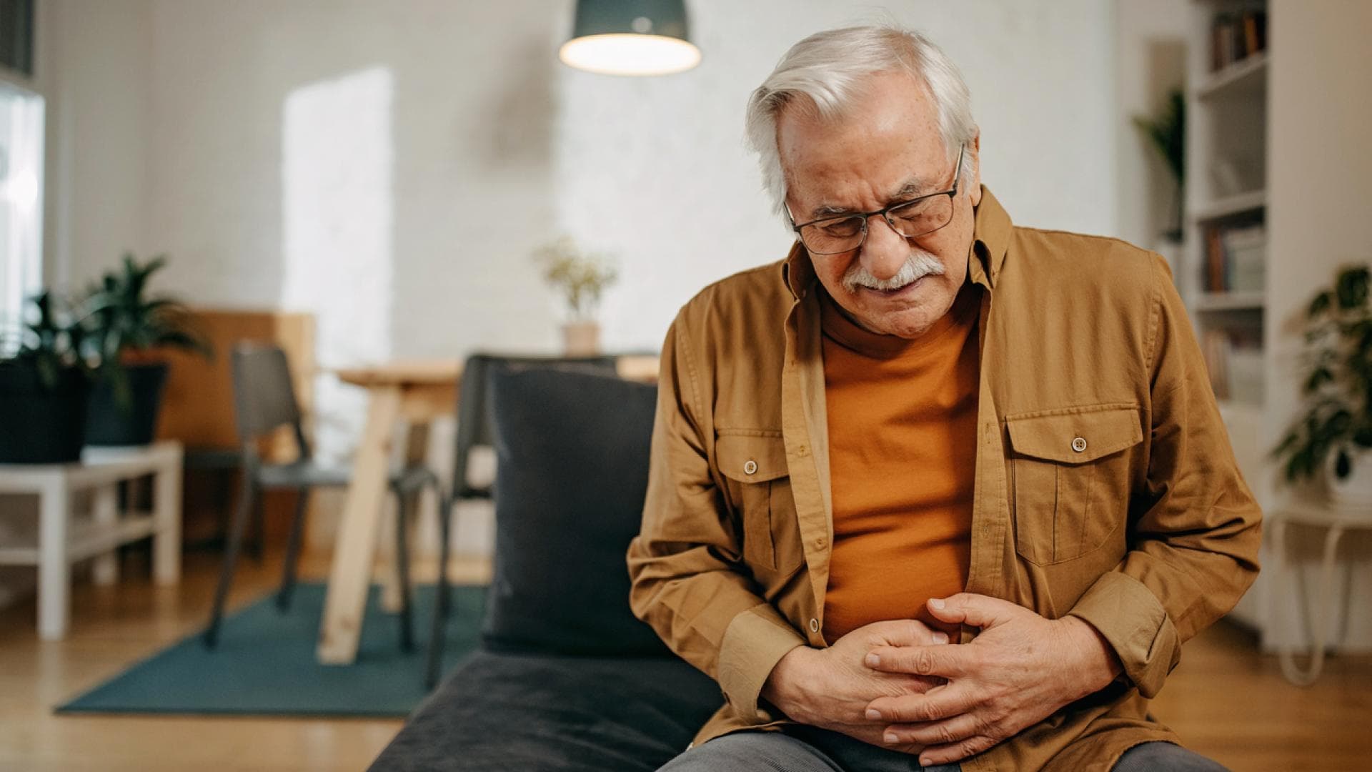 Älterer Mann hält sich schmerzenden Unterbauch