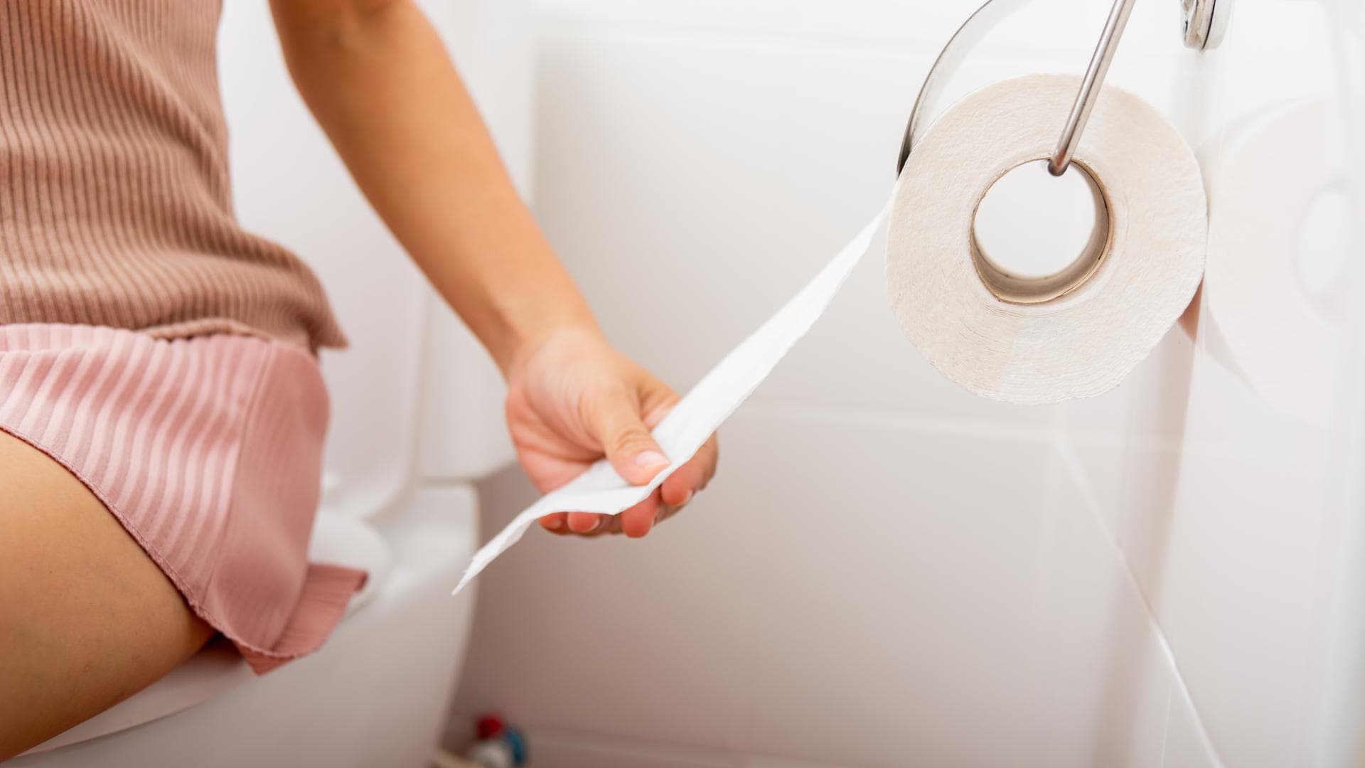 Frau sitzt auf Toilette