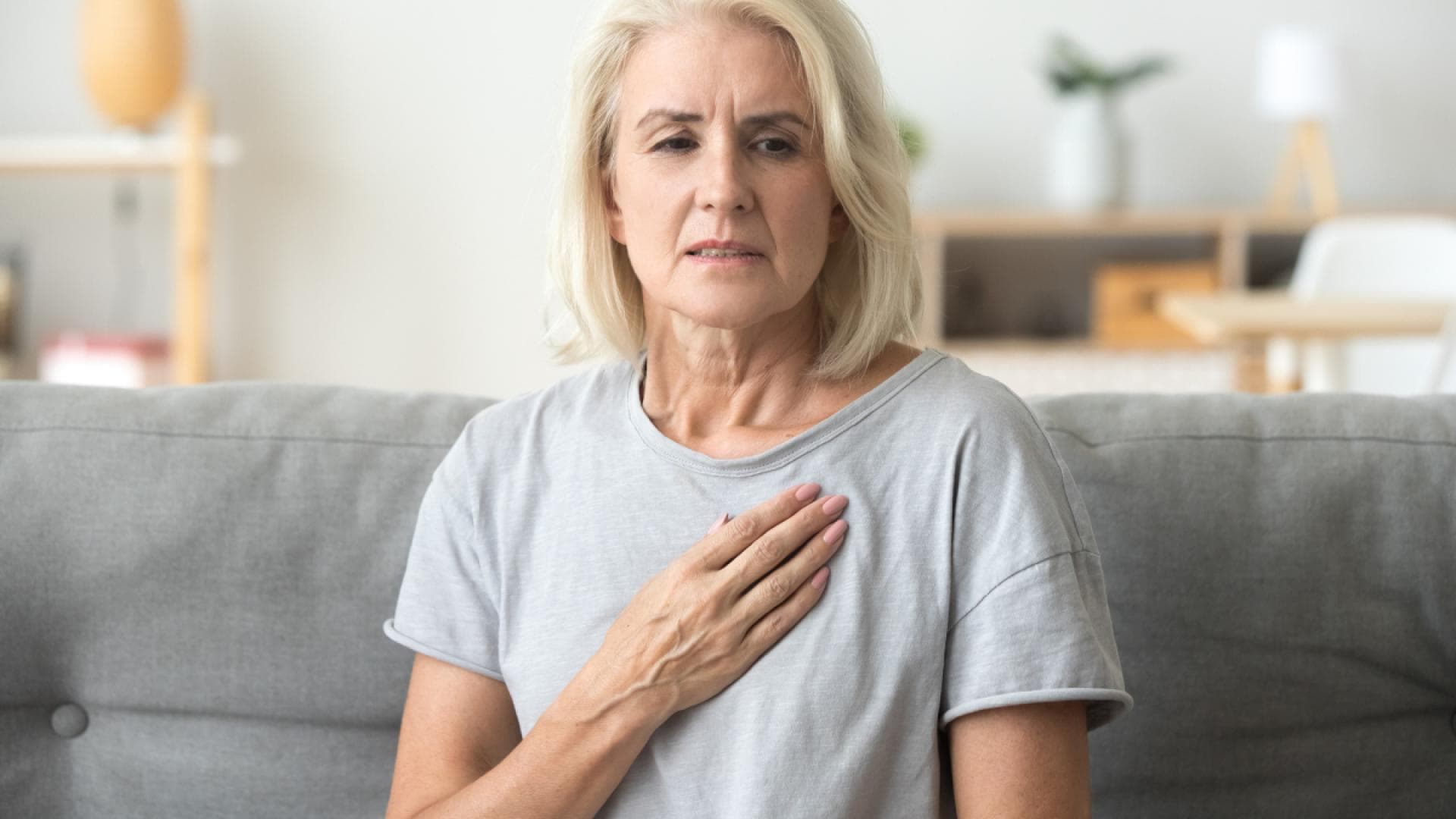 Frau fasst sich an die Brust