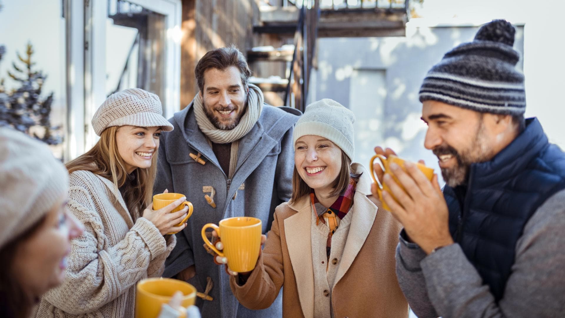 Menschen stehen draußen und trinken gemeinsam Glühwein