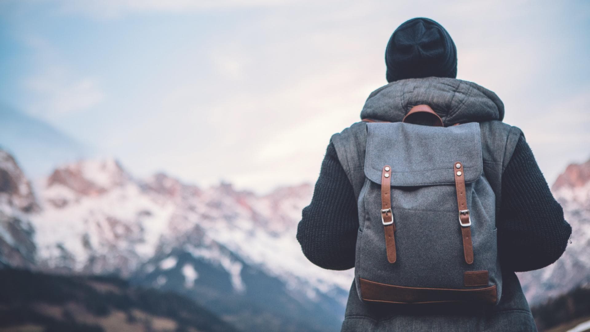 Mann mit Rucksack blickt auf winterliche Berglandschaft