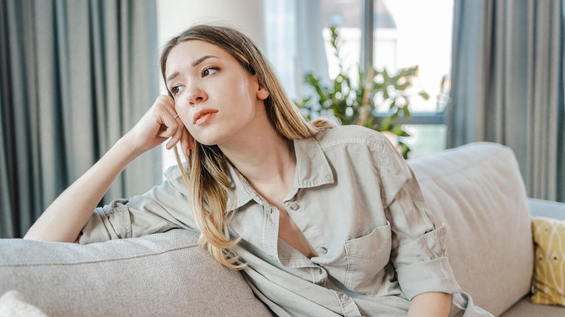 Frau sitzt auf Sofa und guckt traurig Frau sitzt auf Sofa und guckt traurig