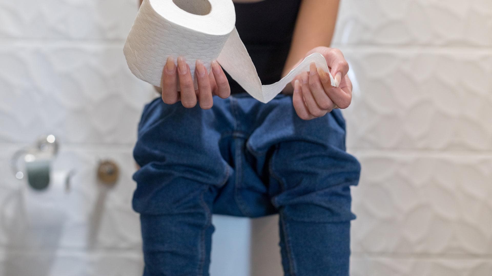 Frau sitzt auf Toilette mit Toilettenpapier in der Hand Frau sitzt auf Toilette mit Toilettenpapier in der Hand