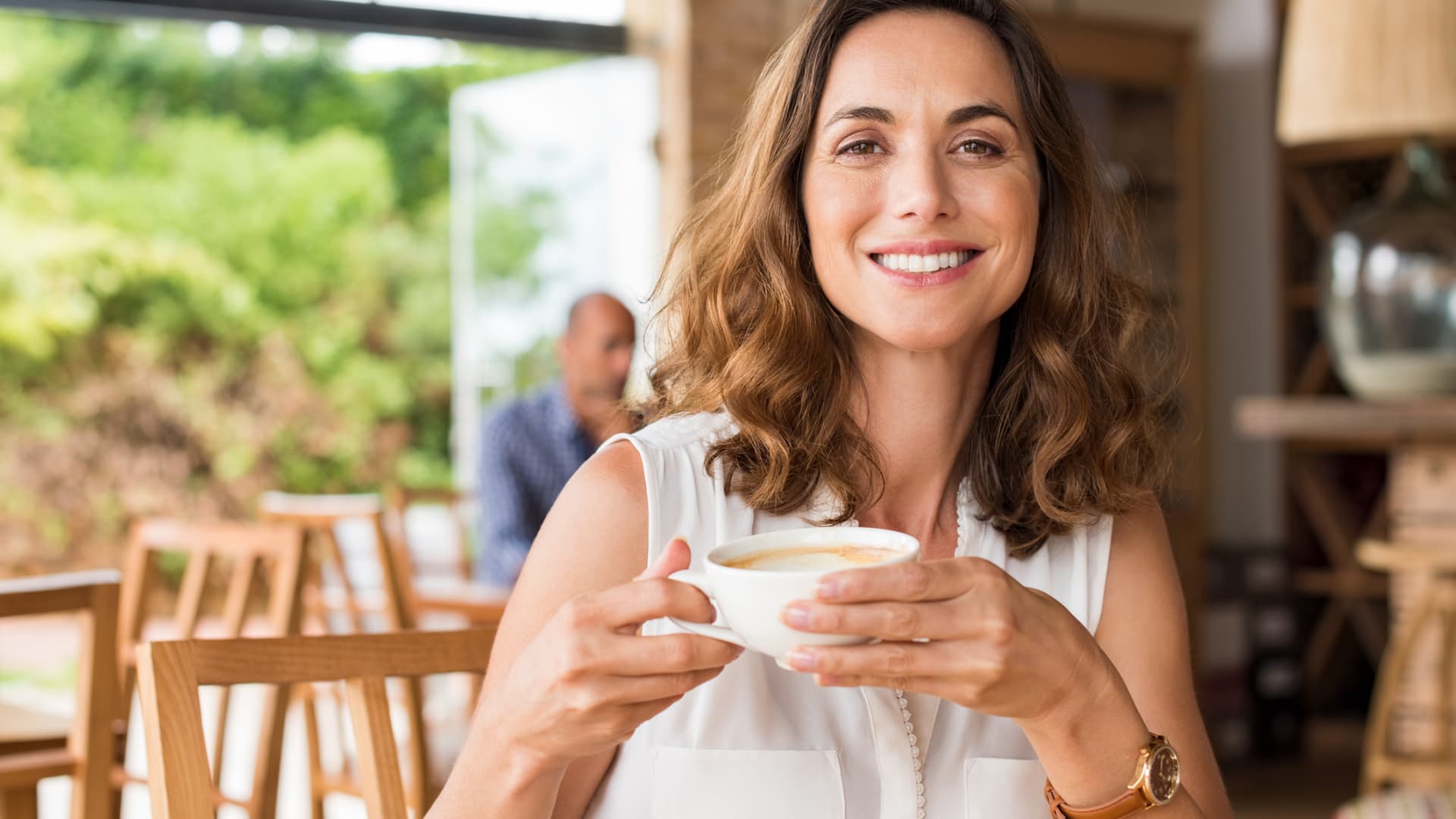 Frau trinkt lächelnd eine Tasse Kaffee