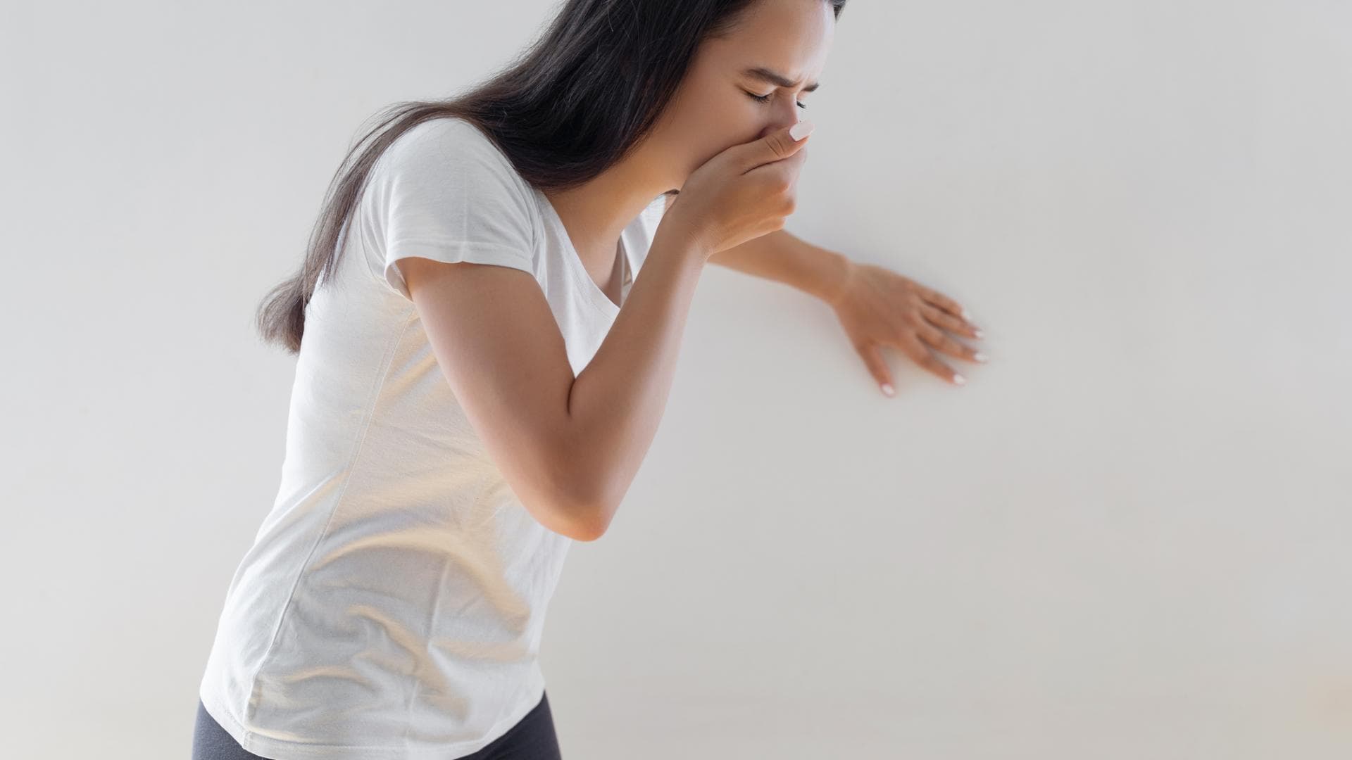 Frau ist übel und sie hält sich die Hand vor den Mund Frau ist übel und sie hält sich die Hand vor den Mund