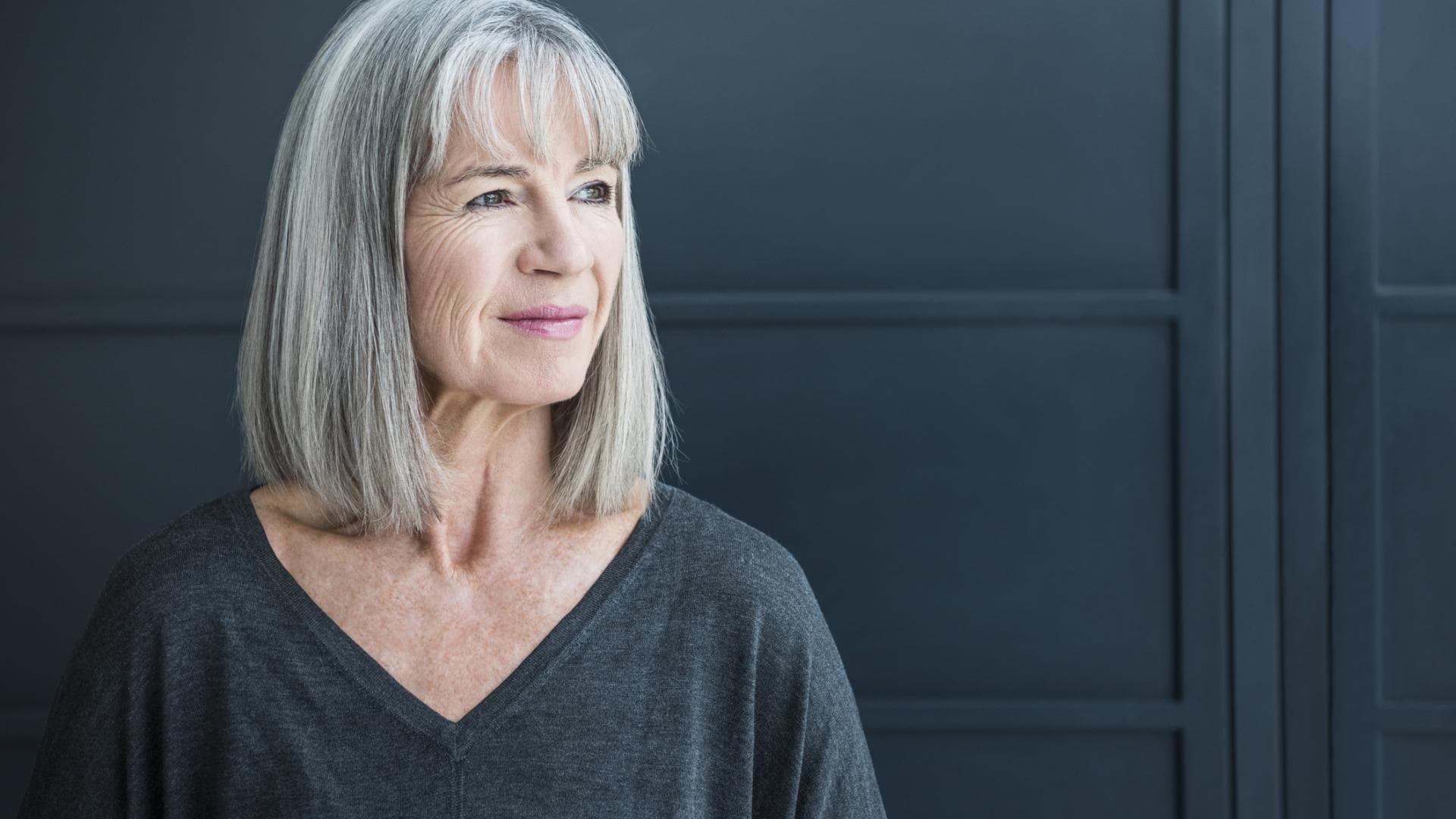 Frau mit grauen Haaren trägt einen Long Bob mit Pony Frau mit grauen Haaren trägt einen Long Bob mit Pony