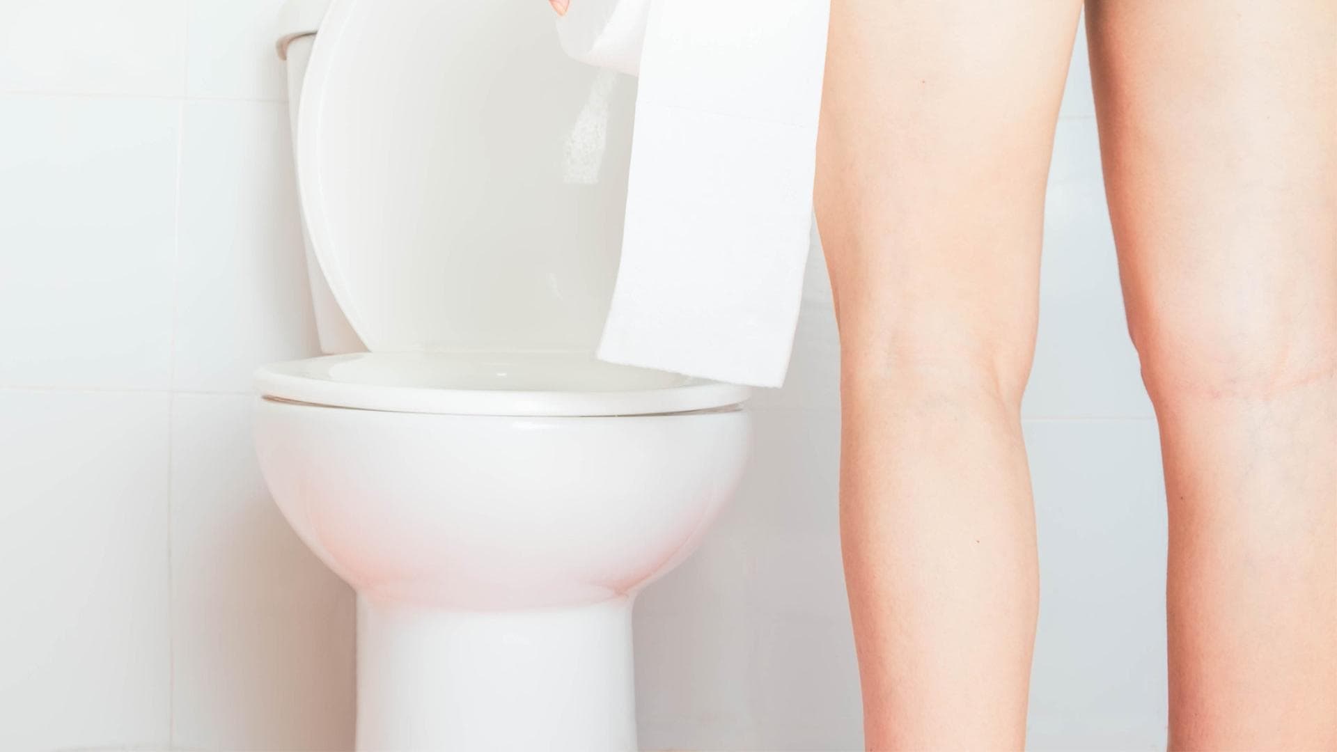 Frau steht vor der Toilette und schaut hinein Frau steht vor der Toilette und schaut hinein
