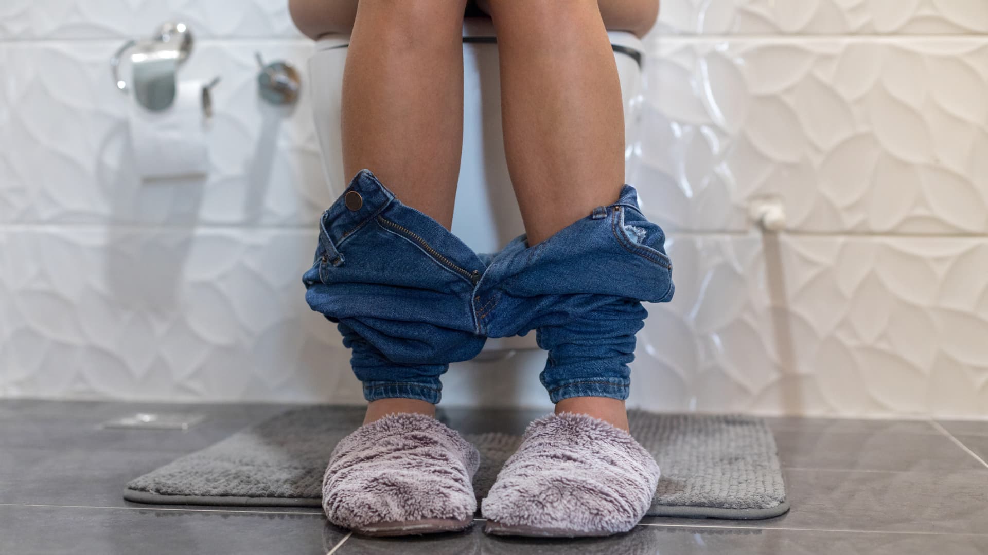 Frau sitzt auf Toilette