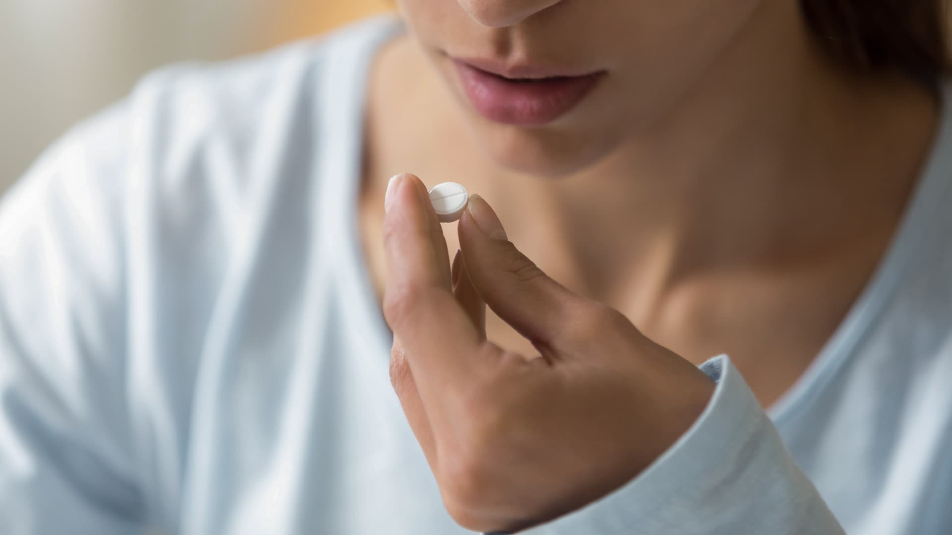 Tramadol wirkt im zentralen Nervensystem, um die Schmerzwahrnehmung zu verändern. Frau nimmt eine Tablette