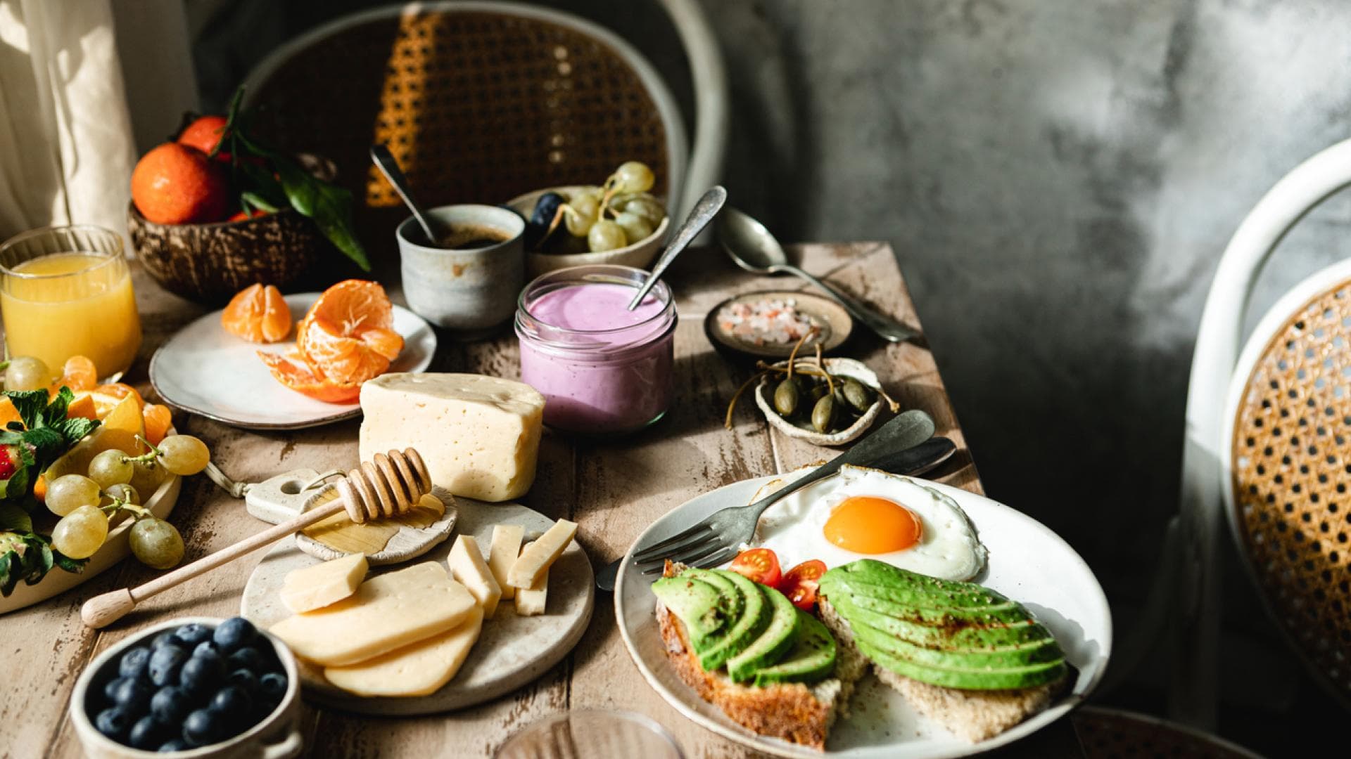 Eine ausgewogene pflanzliche Ernährung ist aktuelle DGE-Empfehlung Bunt gedeckter Frühstückstisch mit Käse, Obst, Joghurt und Avocado-Brot mit Spiegelei
