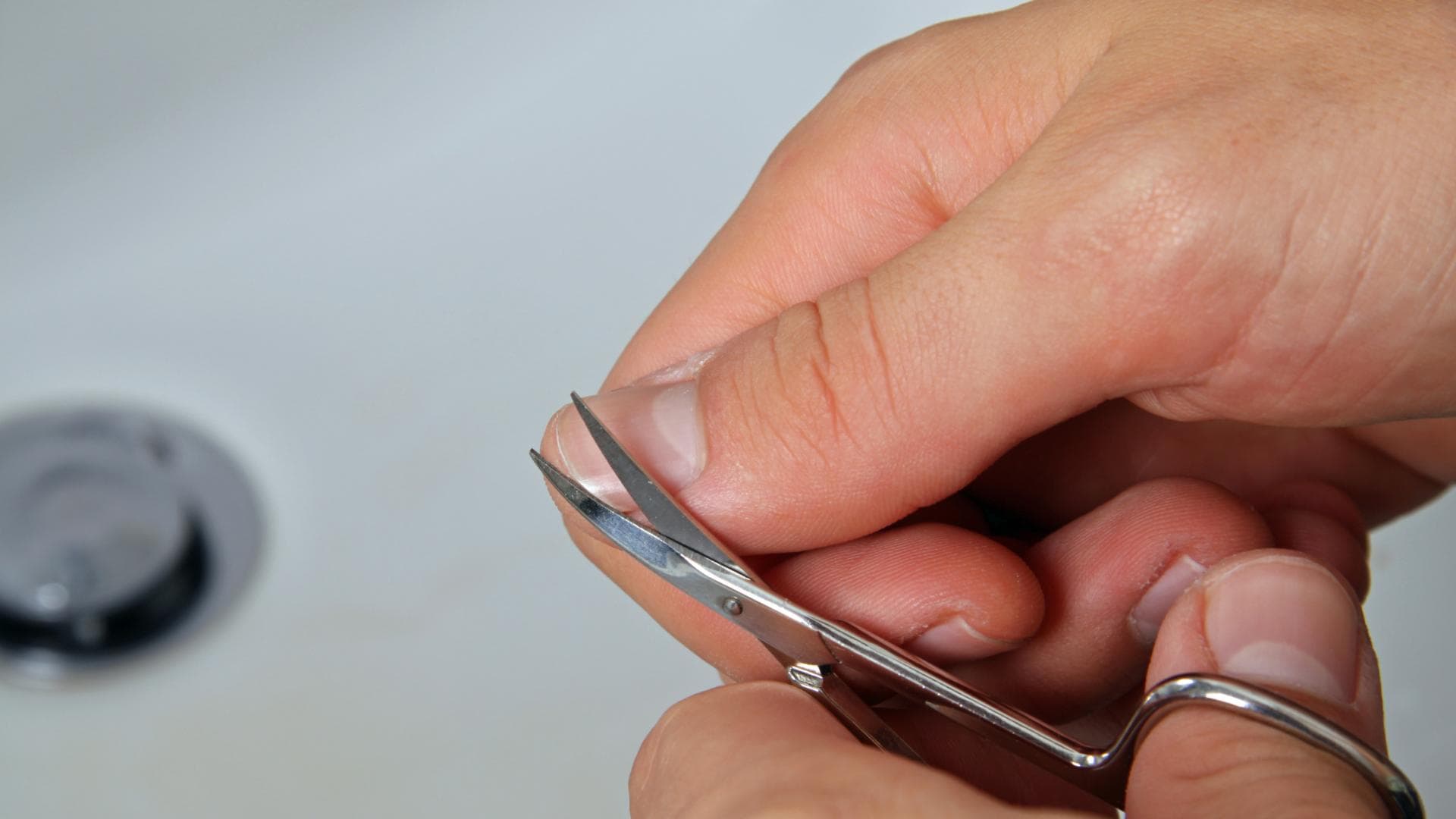 Frau schneidet sich den Daumennagel mit einer Nagelschere Frau schneidet sich den Daumennagel mit einer Nagelschere