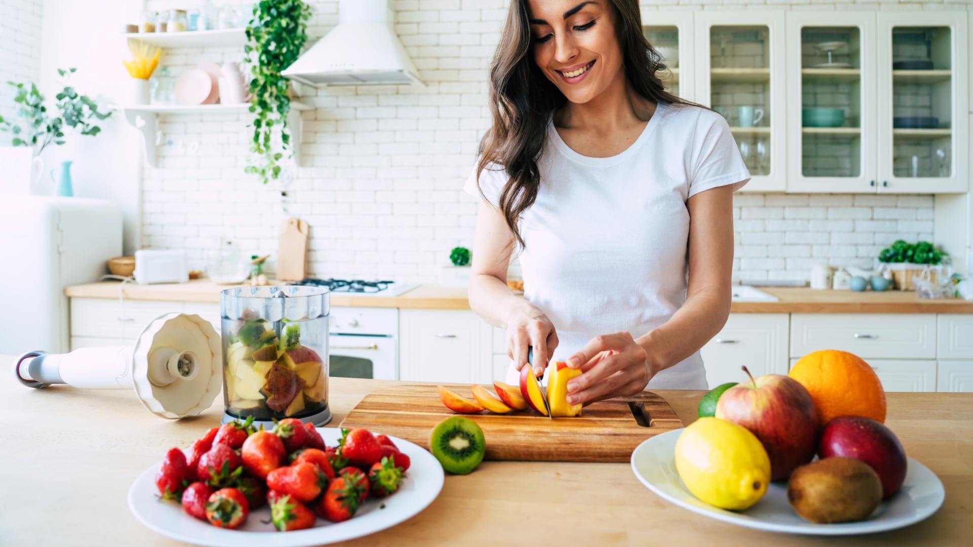 Frau schneidet Obst für einen Smoothie Frau schneidet Obst für einen Smoothie