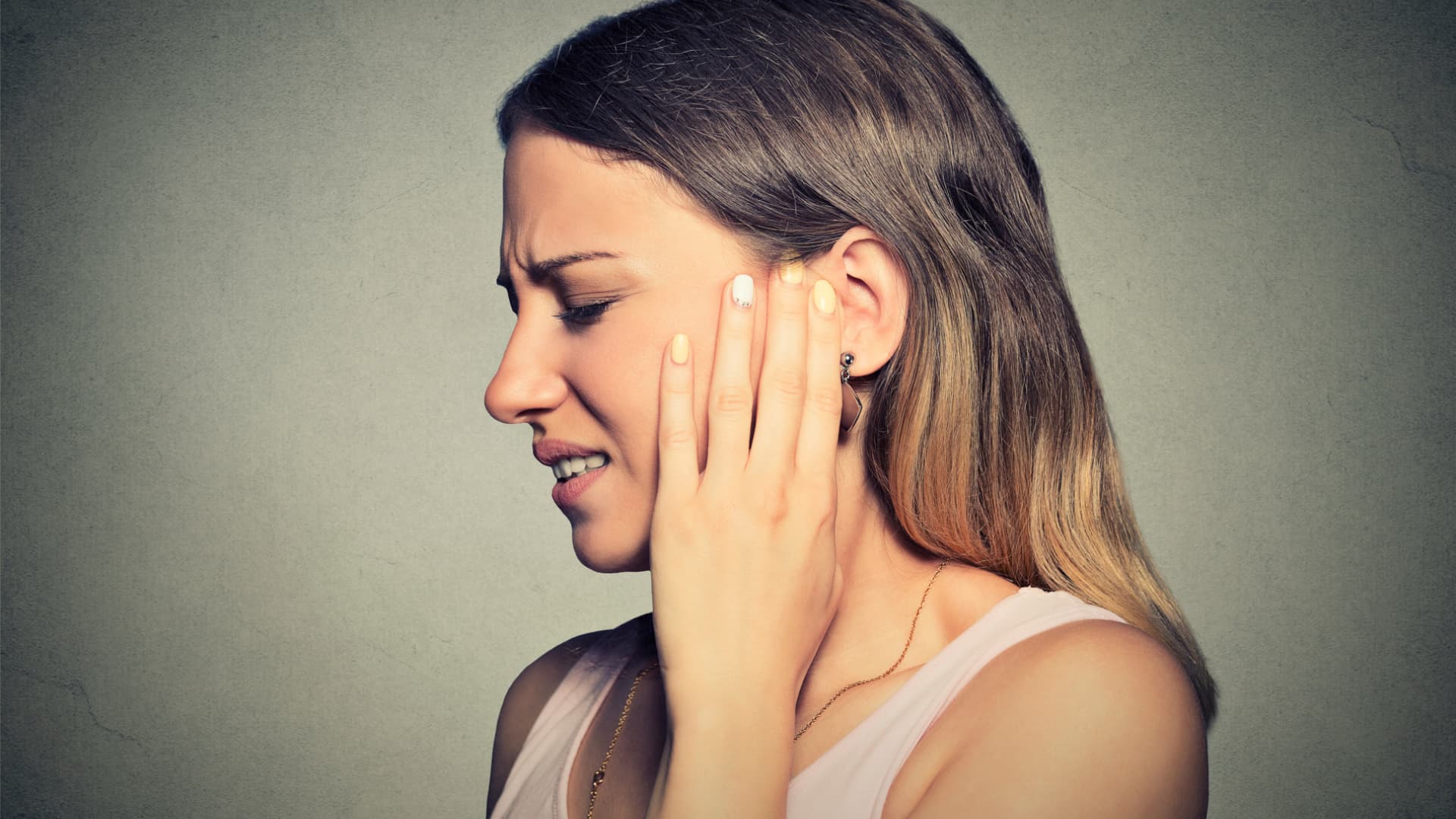 Ein Knalltrauma kann durch laute Geräusche ausgelöst werden. Frau hat Ohrenschmerzen
