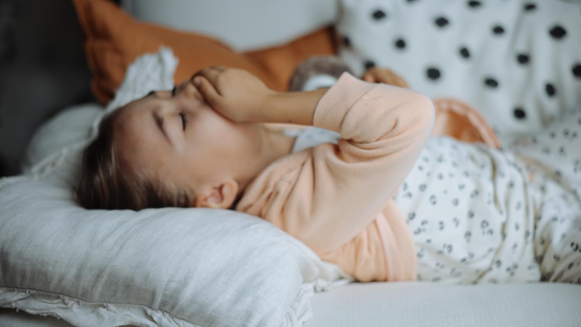 Mädchen liegt im Bett und hustet.