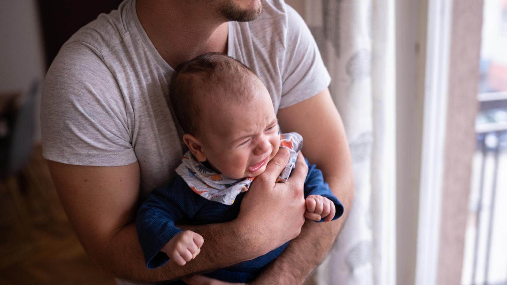 Vater hält sein weinendes Kind Koliken bei Babys: Vater hält sein weinendes Kind.