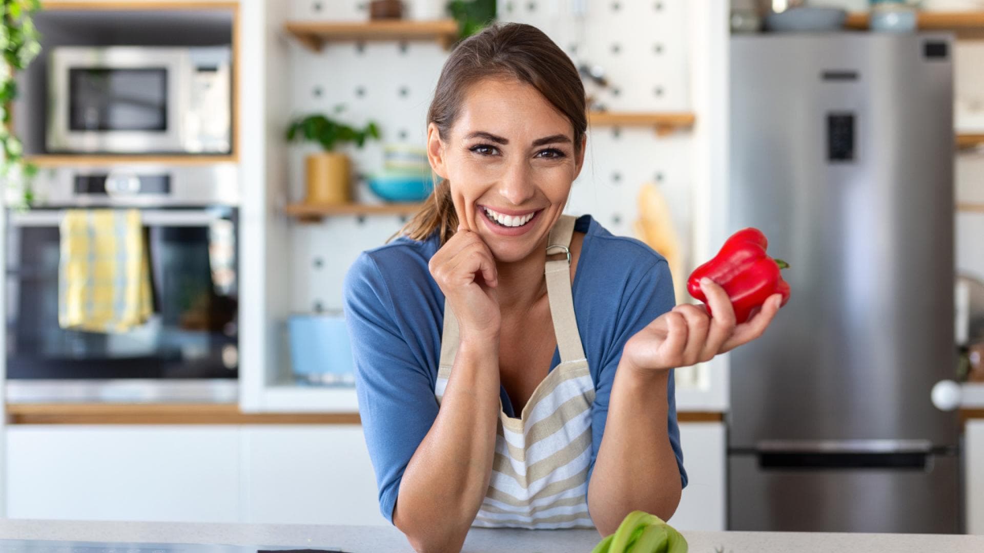 Frau in der Küche hält Paprika in den Händen Frau in der Küche hält Paprika in den Händen