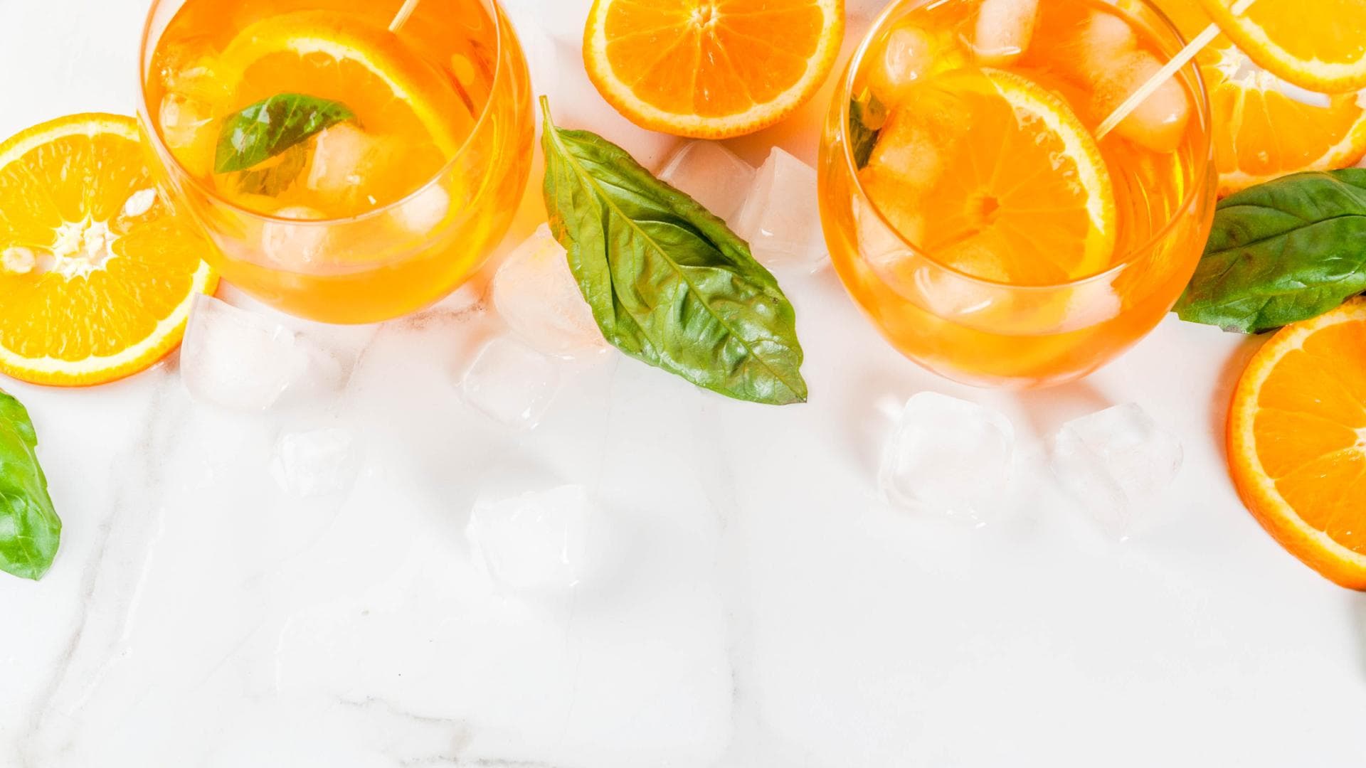 Gläser mit Orangenlimonade und Basilikum zwischen Eiswürfeln. Gläser mit Orangenlimonade und Basilikum zwischen Eiswürfeln.