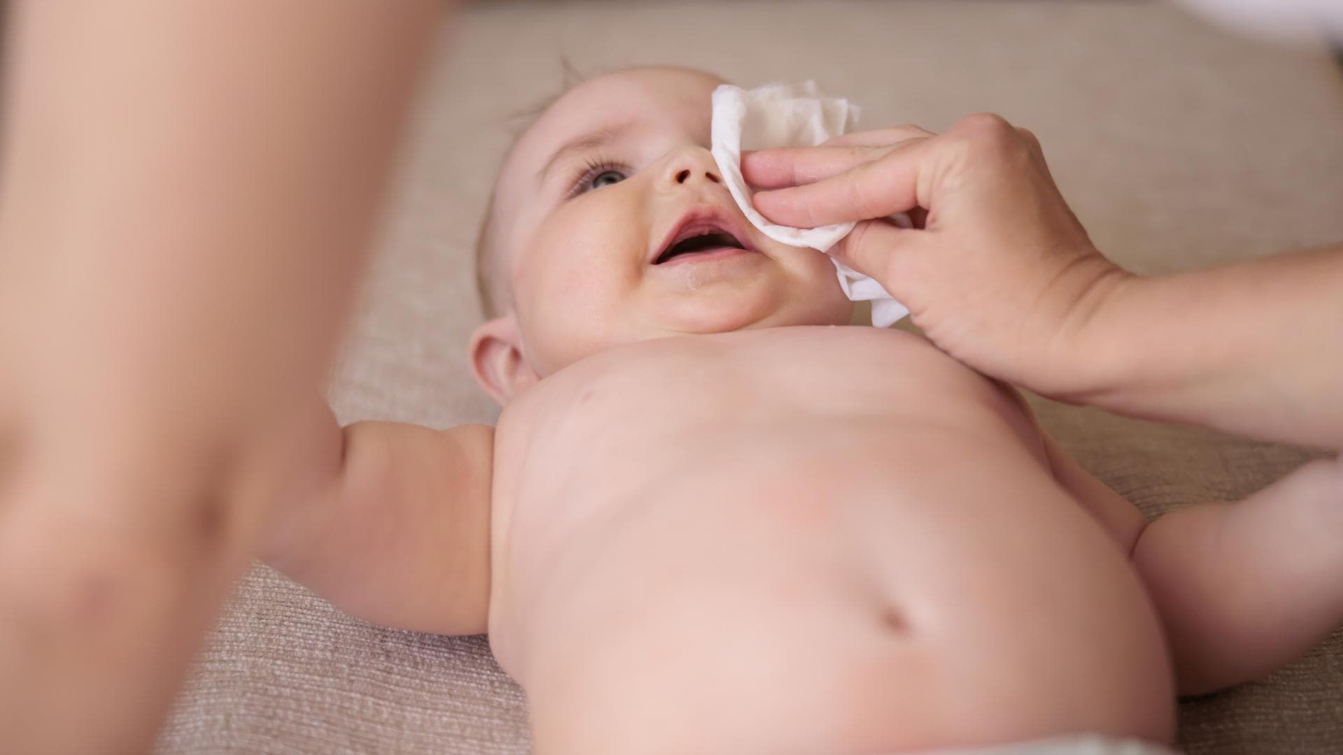 Mutter wischt ein verklebtes Auge beim Baby sauber. Mutter wischt ein verklebtes Auge beim Baby sauber.