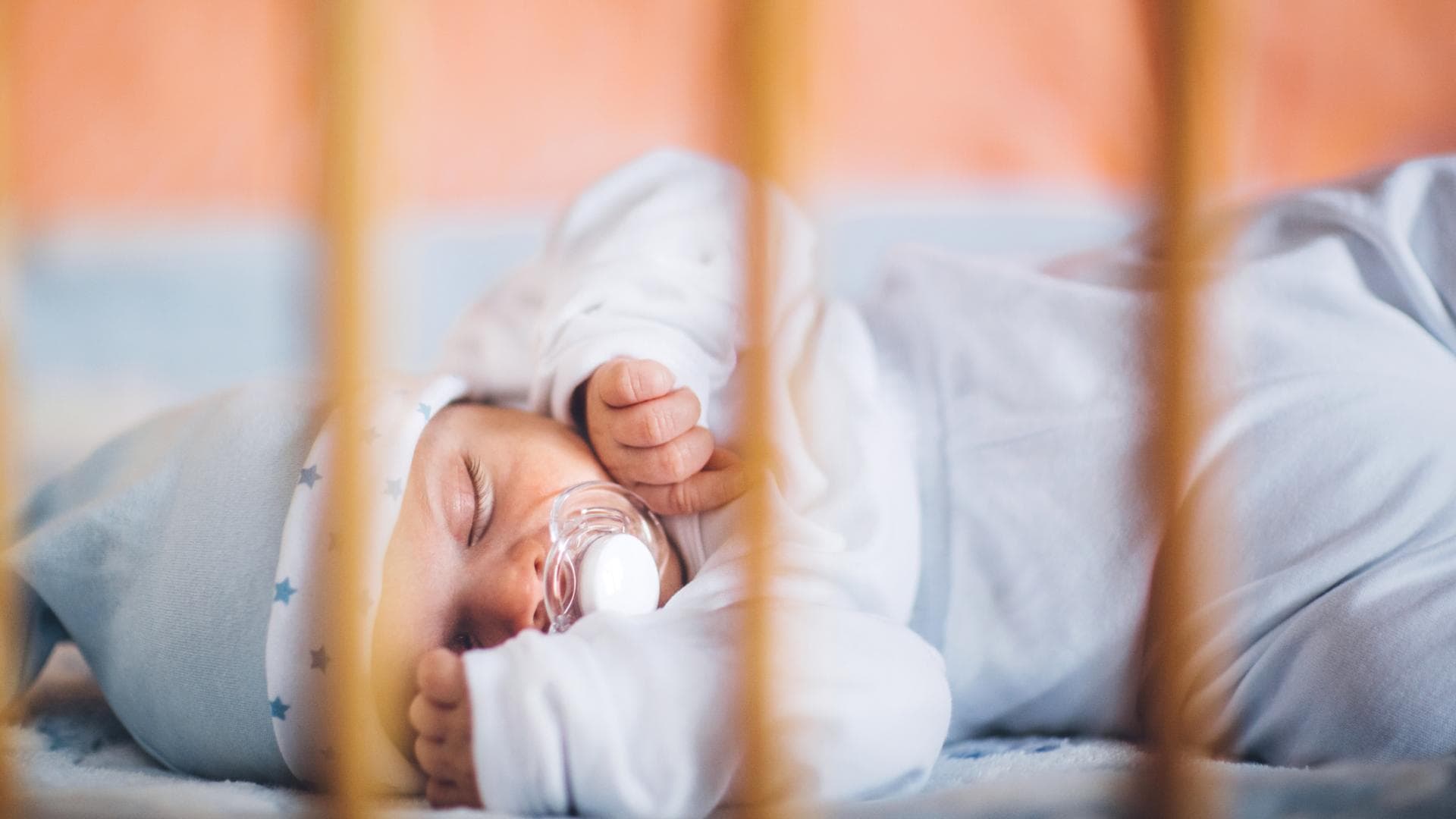 Ein Baby schläft in einem Bettchen mit einem Schnuller. Ein Baby schläft in einem Bettchen mit einem Schnuller.
