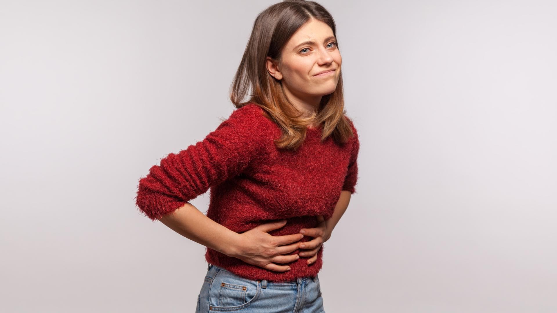 Frau hält sich den Bauch, weil sie Hunger hat Frau hält sich den Bauch, weil sie Hunger hat