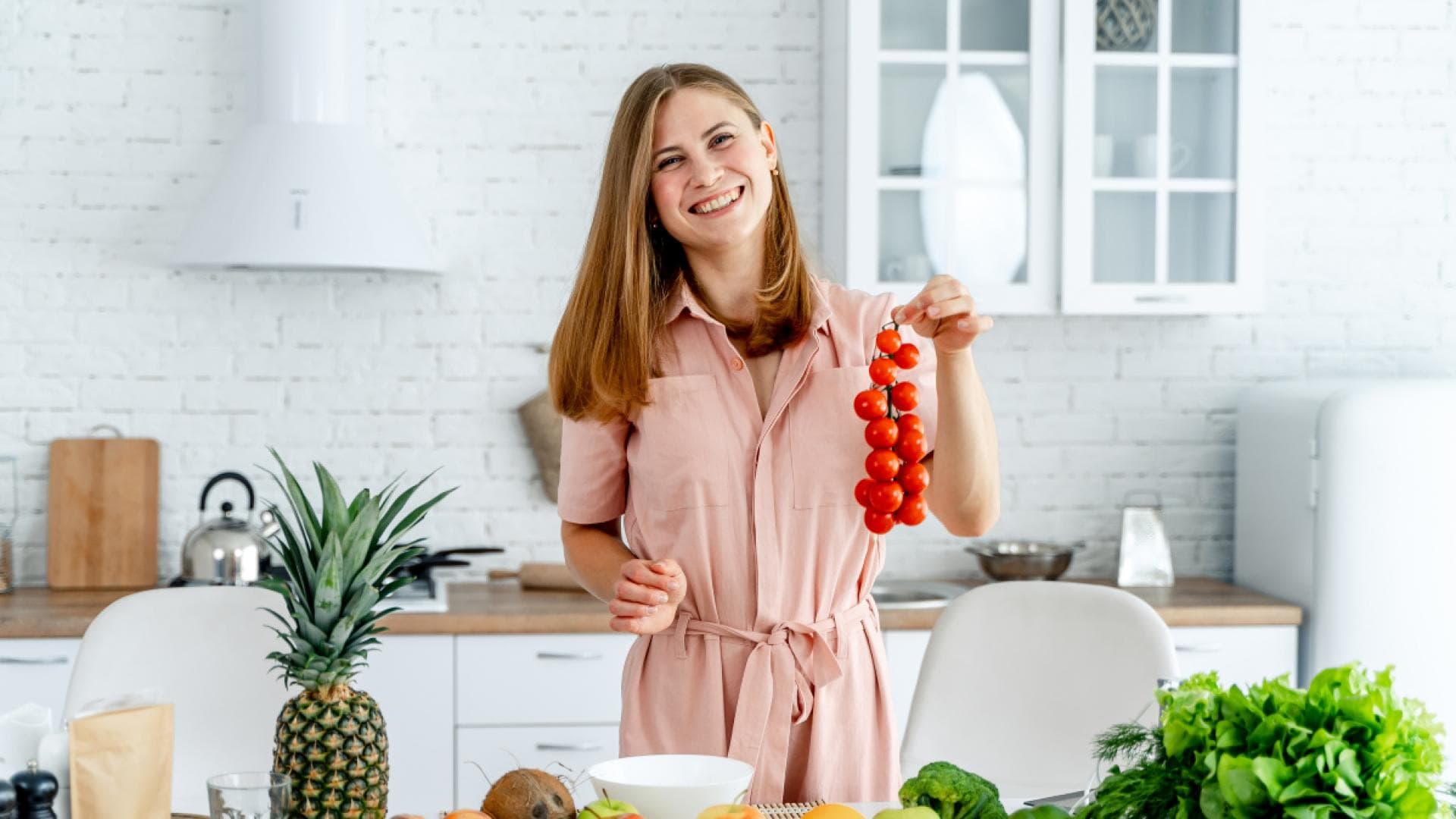 Frau steht in der Küche und bereitet eine Mahlzeit mit Gemüse und Obst zu. Frau steht in der Küche und bereitet eine Mahlzeit mit Gemüse und Obst zu.
