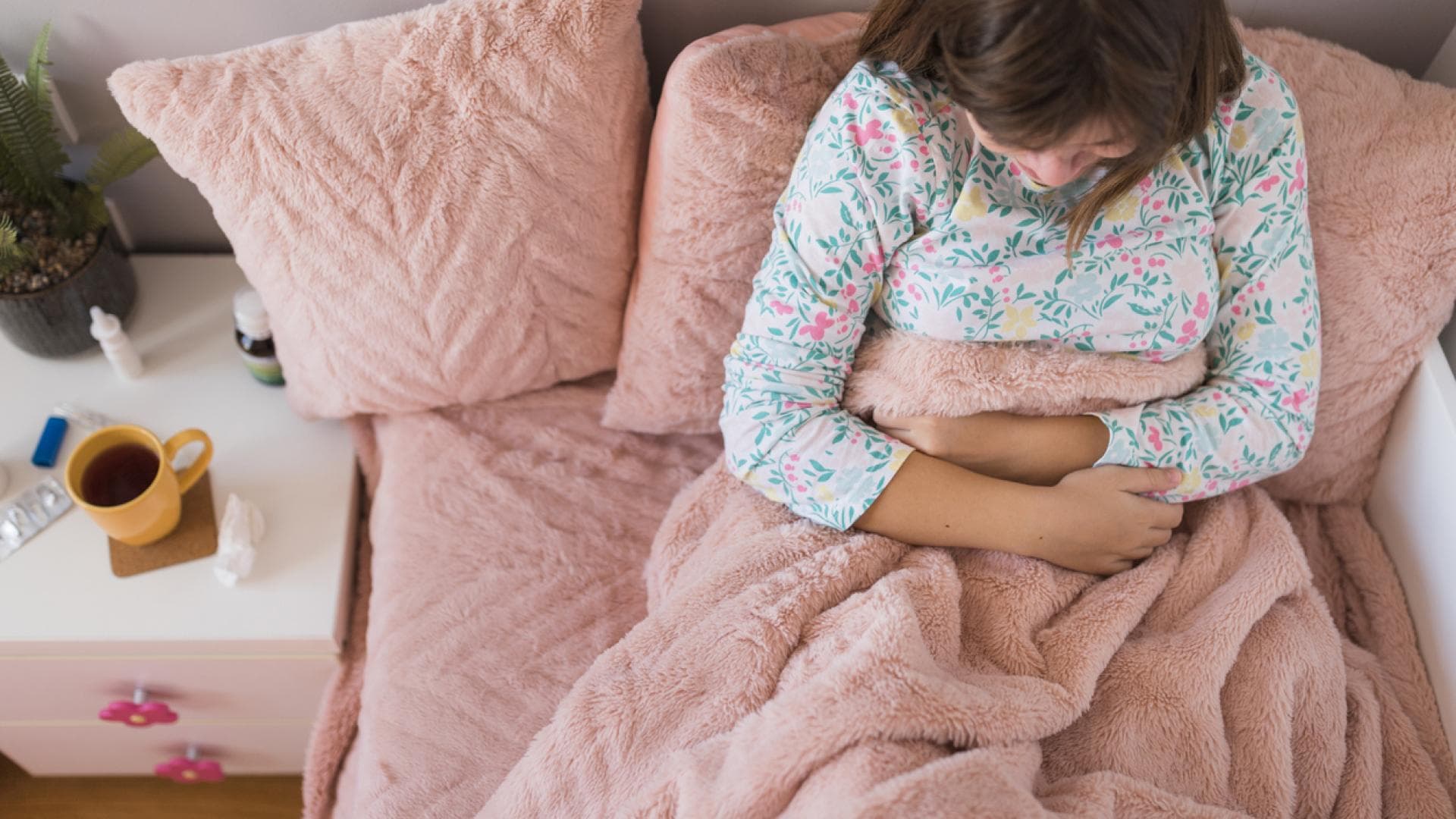 Rotaviren-Symptome sind Durchfall und Erbrechen Junge Frau liegt im Bett hält sich den Bauch
