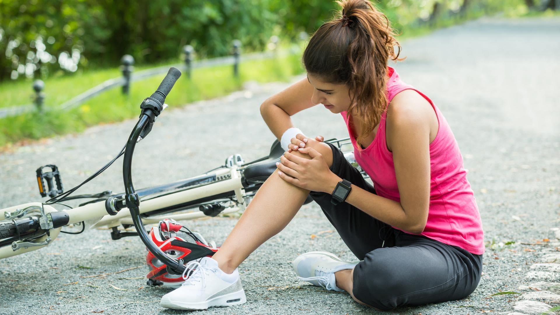 Junge Frau hatte einen Unfall mit dem Fahrrad und hält sich das Knie. Junge Frau hatte einen Unfall mit dem Fahrrad und hält sich das Knie.