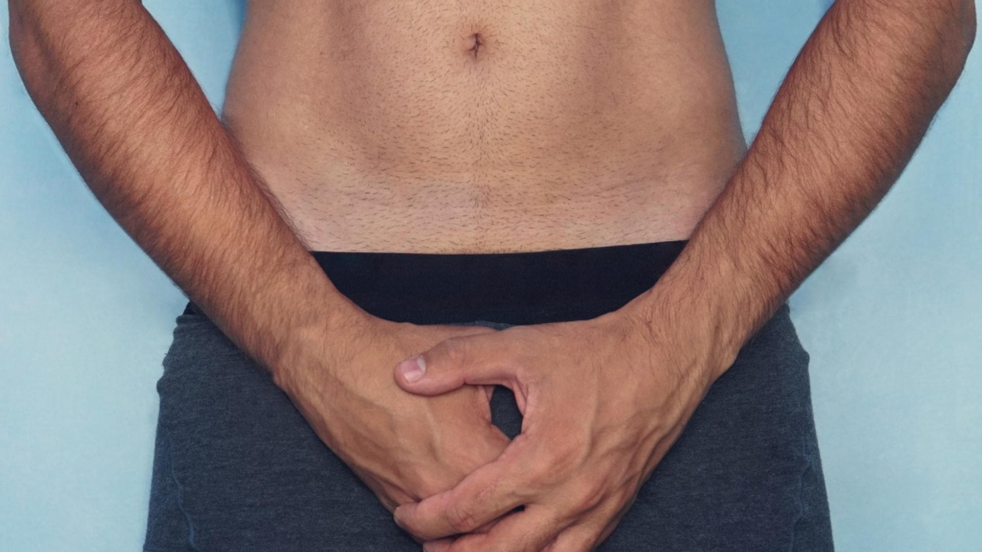 Mann hält sich die Hände schützend vor den Intimbereich Mann hält sich die Hände schützend vor den Intimbereich