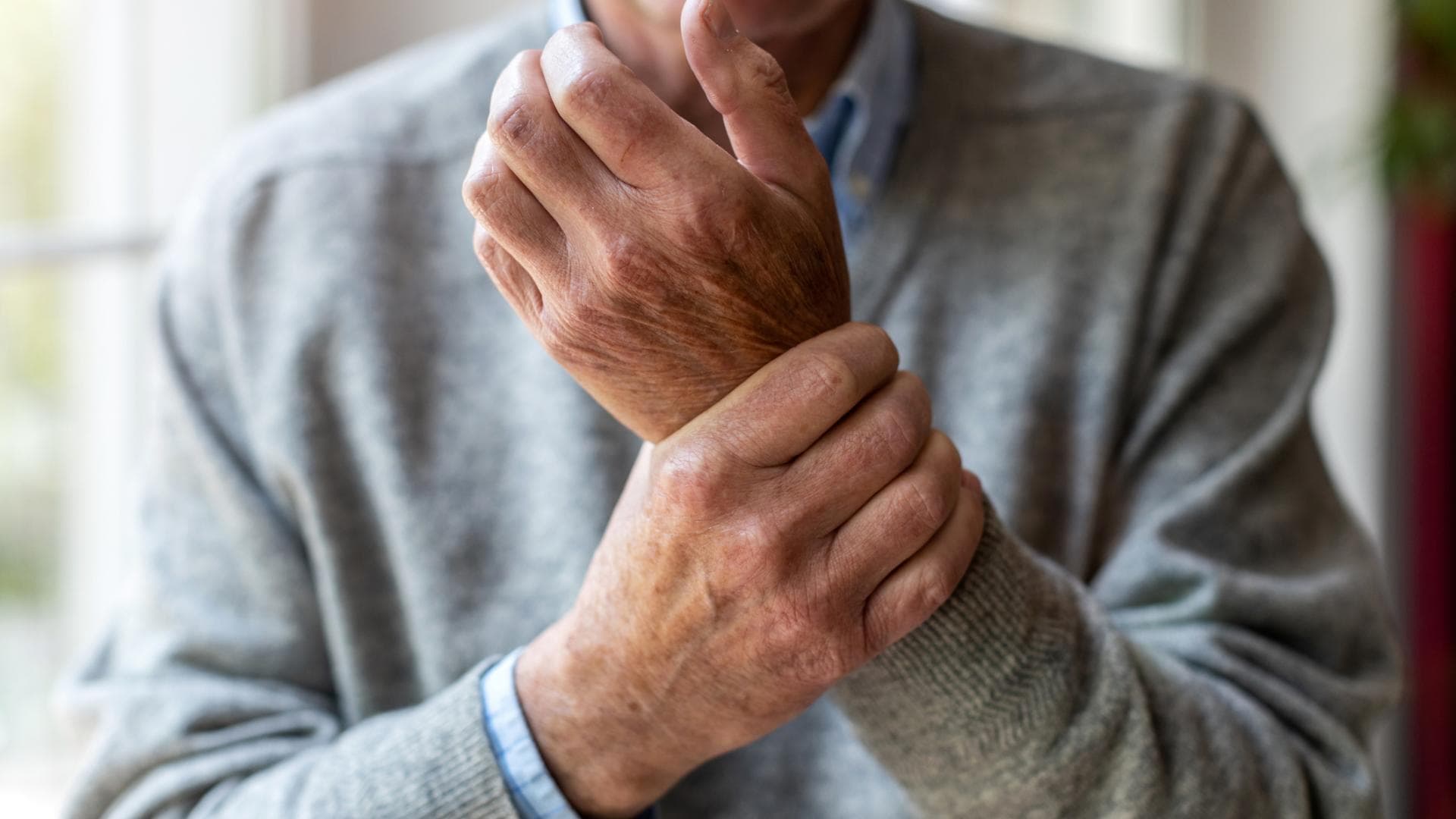 Mann hält sich die schmerzende Hand Mann hält sich die schmerzende Hand