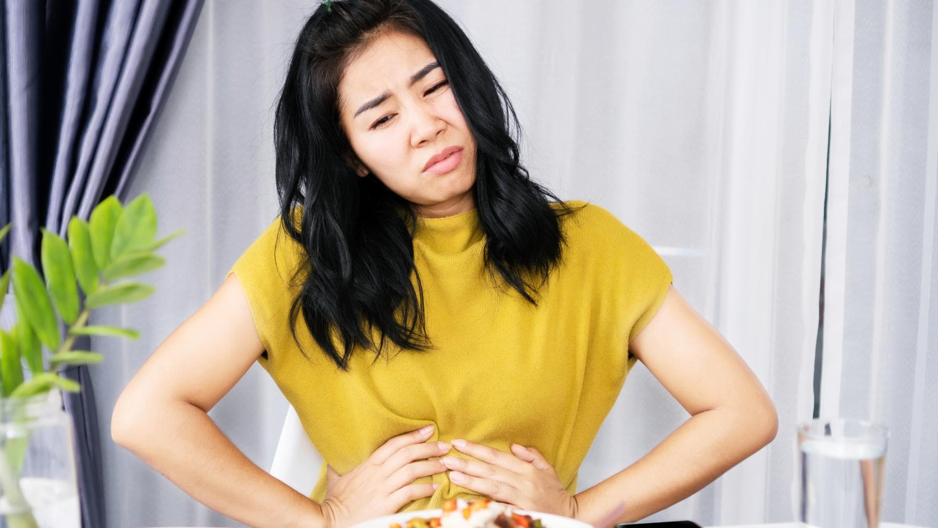 Frau hält sich den Bauch beim Essen Frau hält sich den Bauch beim Essen