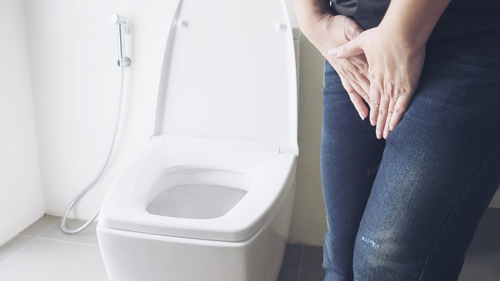 Person hält sich vor Toilette die Hände vorm Schritt Person hält sich vor Toilette die Hände vorm Schritt
