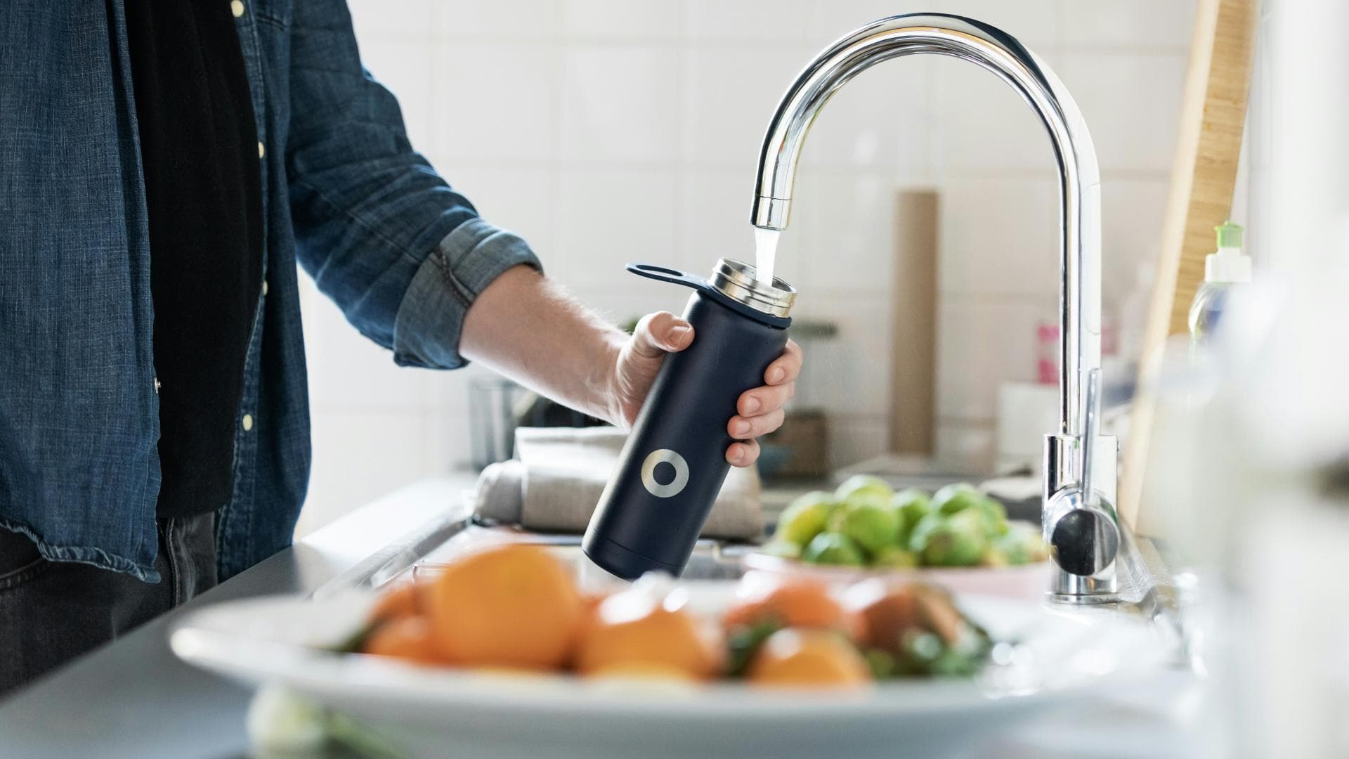 Mann füllt Flasche am Wasserhahn auf Mann füllt Flasche am Wasserhahn auf