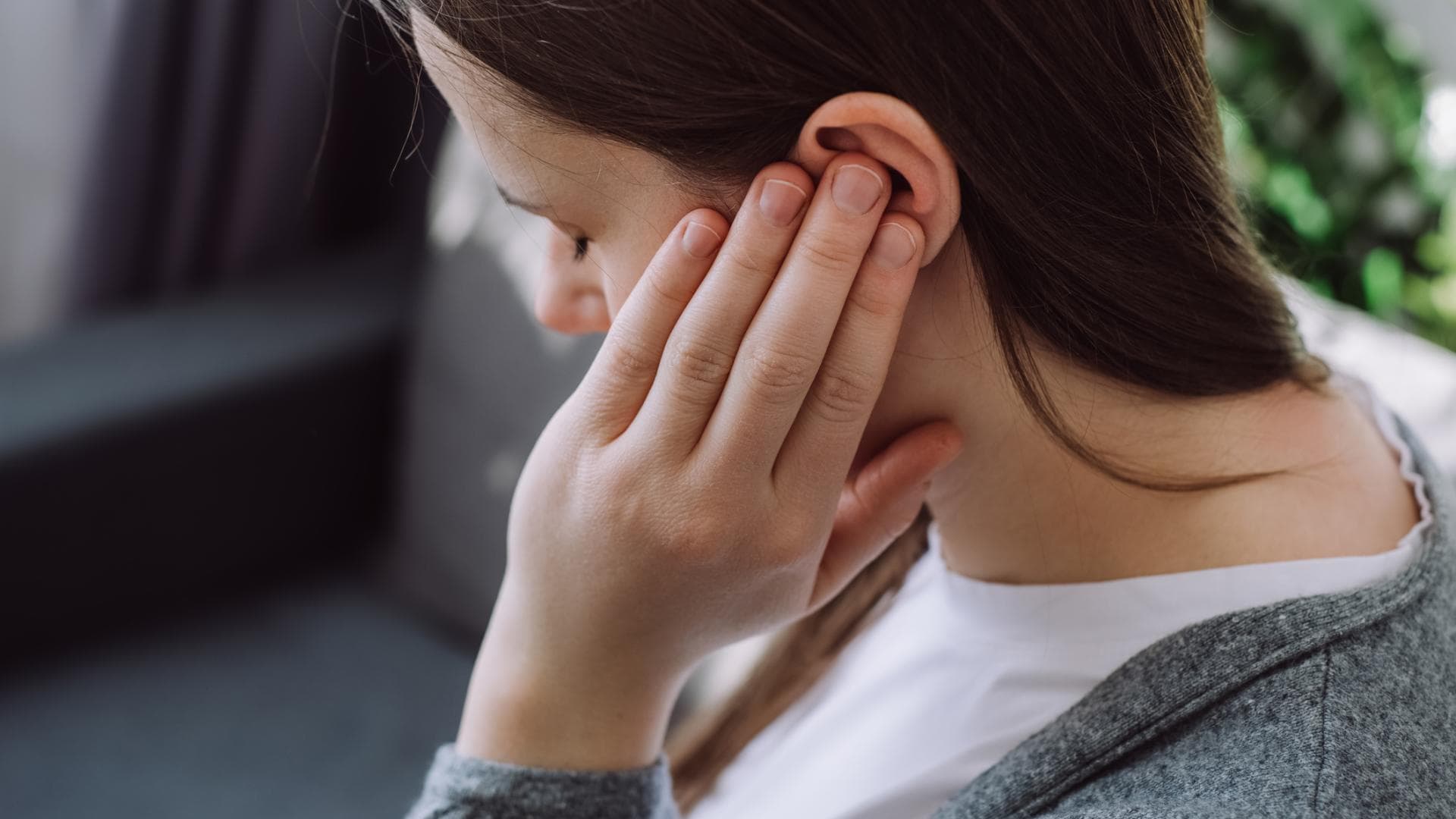 Frau hält sich das schmerzende Ohr Frau hält sich das schmerzende Ohr