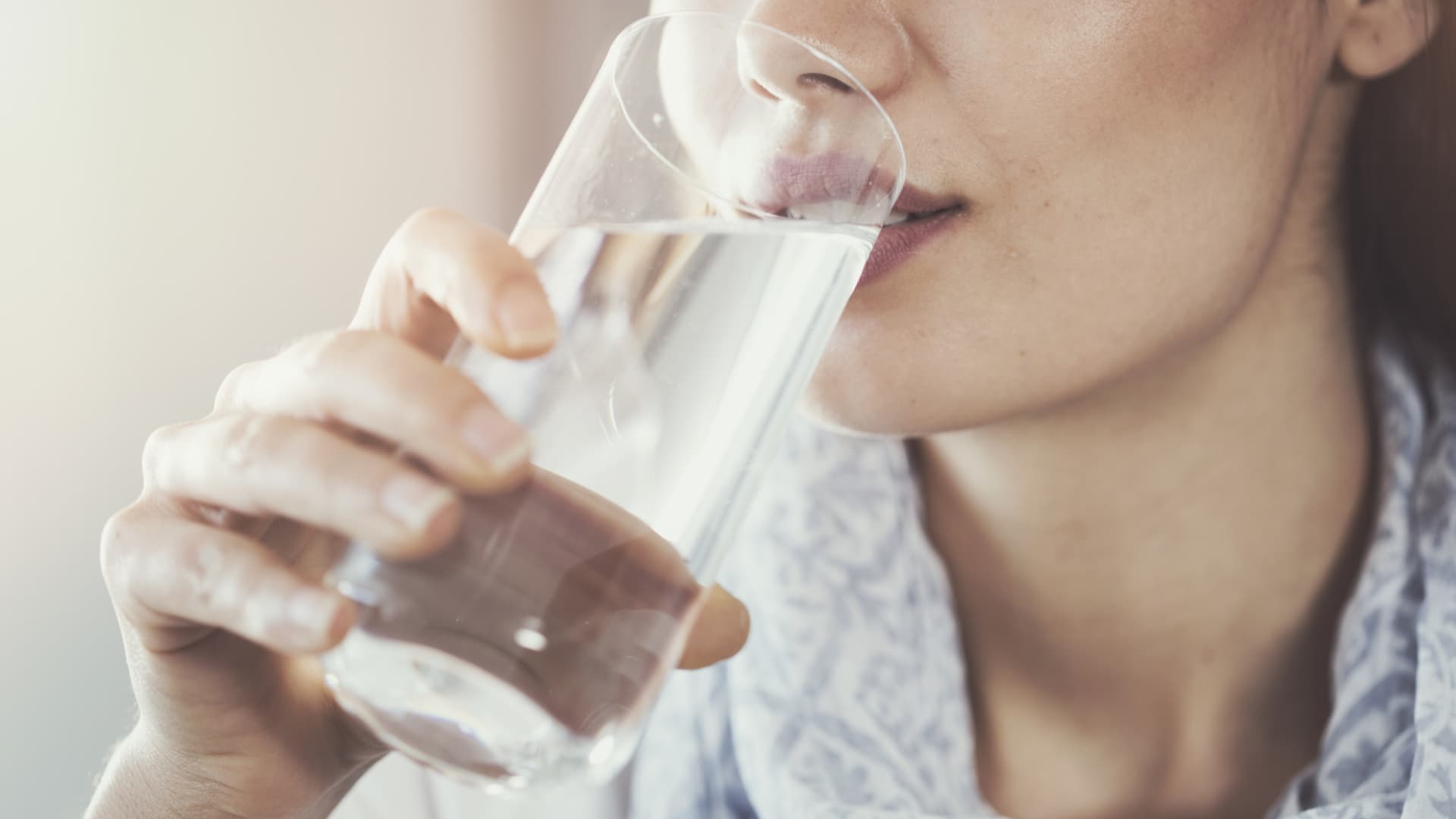 Polydipsie ist ein Zustand, bei dem Betroffene übermäßig viel Wasser trinken. Frau trinkt Wasser